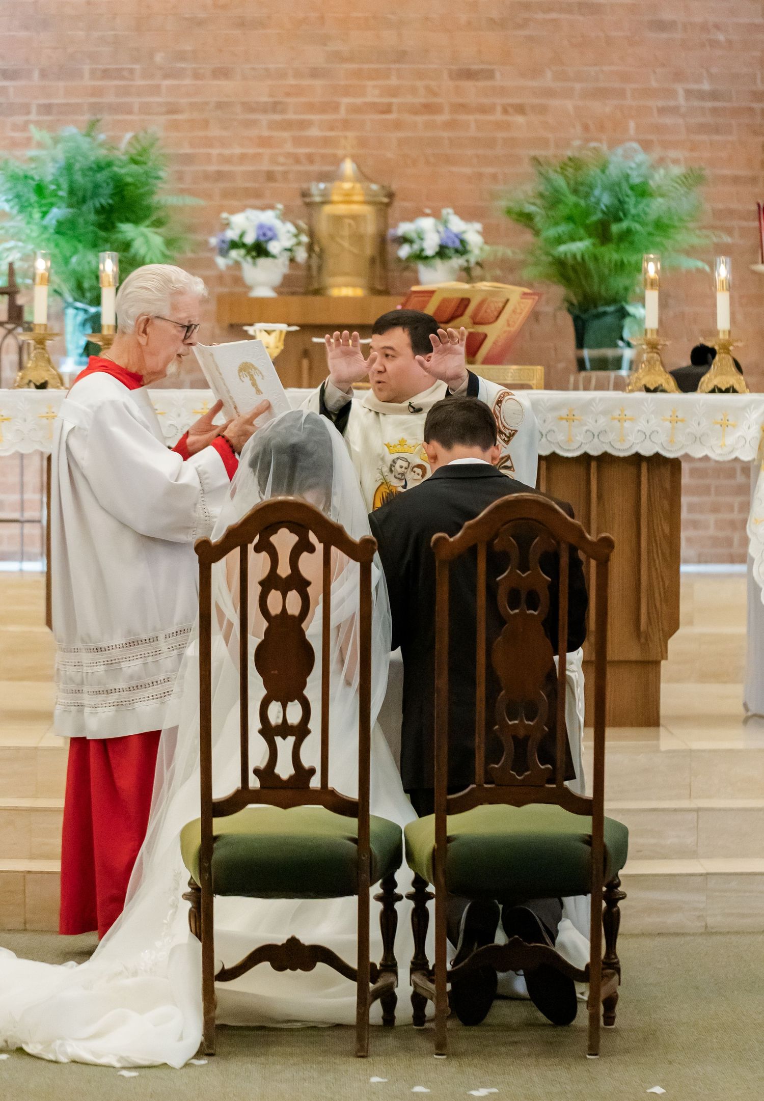 Ornate wooden chairs and white decorations arranged at church altar.