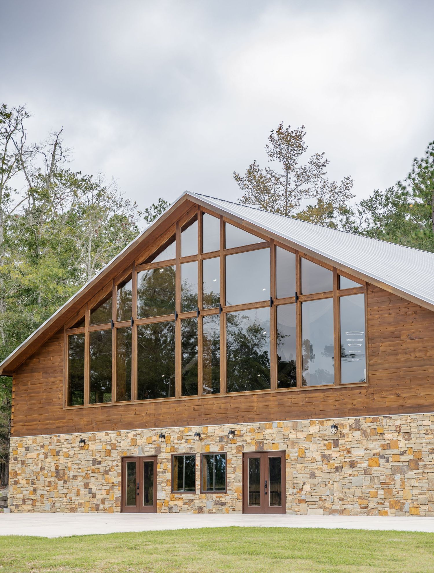 Modern lodge building with wood siding, stone base, and large angled windows showcases rustic architectural design.