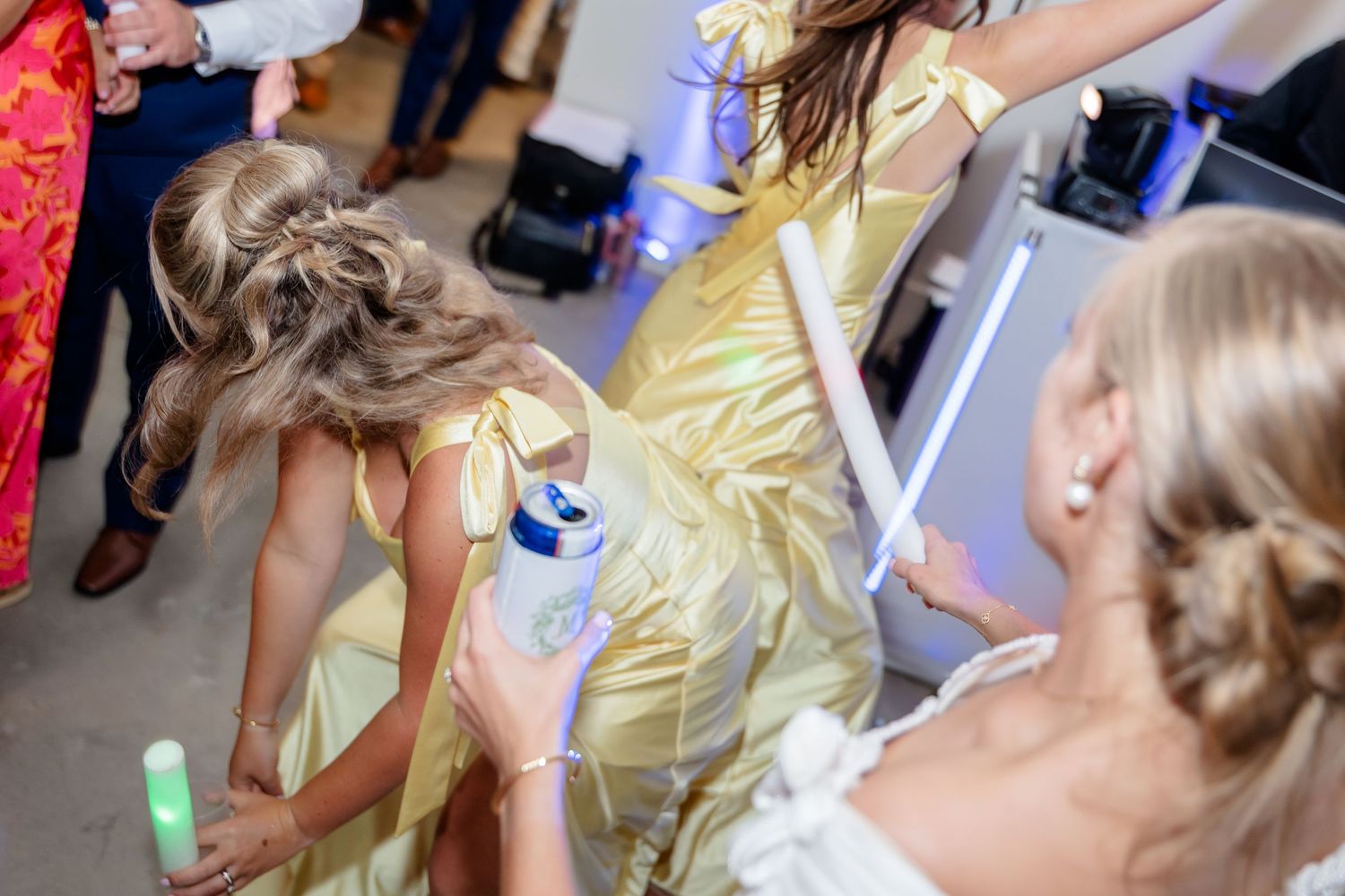 Wedding guests dancing with glowing batons under industrial ceiling lights.