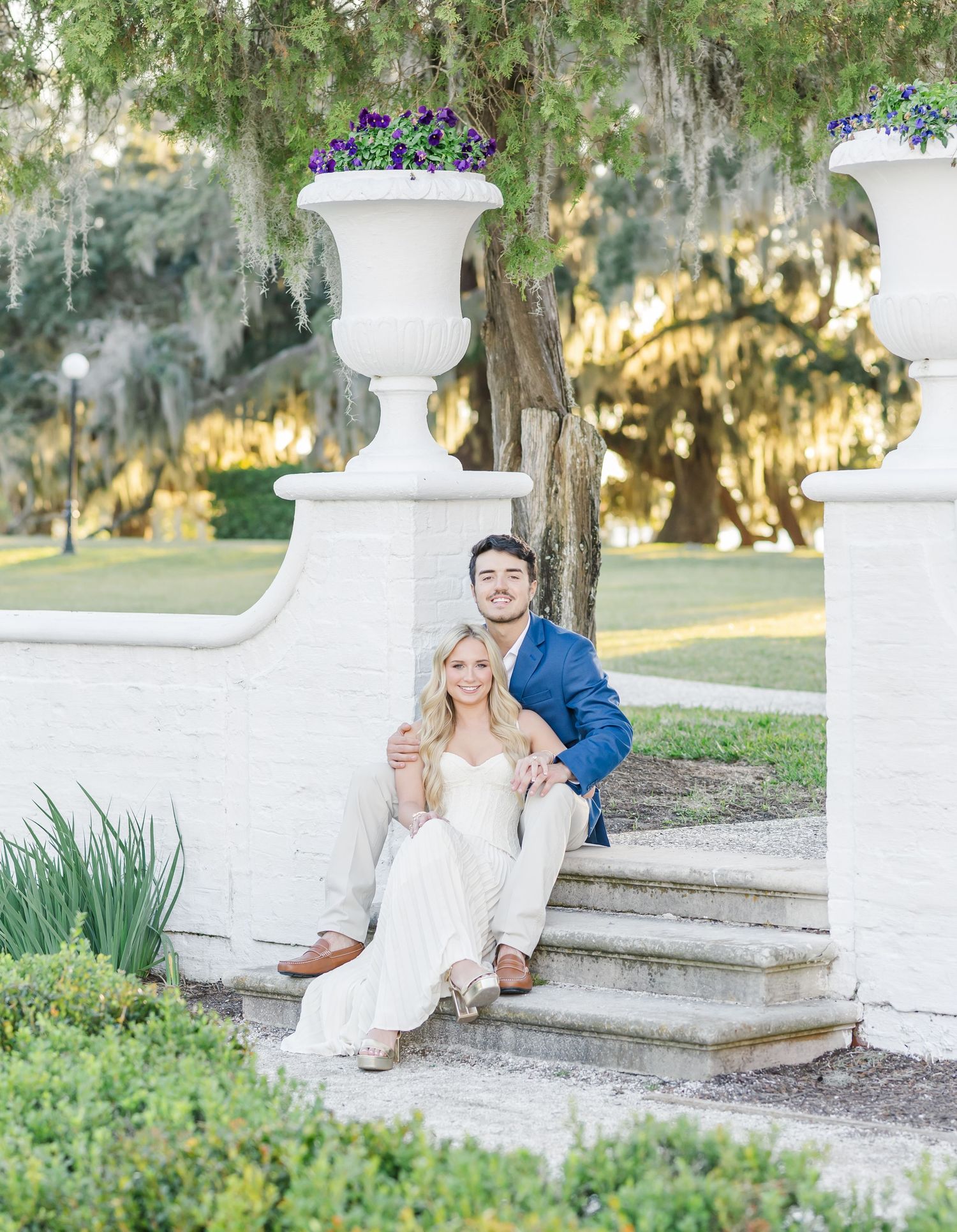 A romantic photoshoot on white stone steps surrounded by lush greenery and Spanish moss.