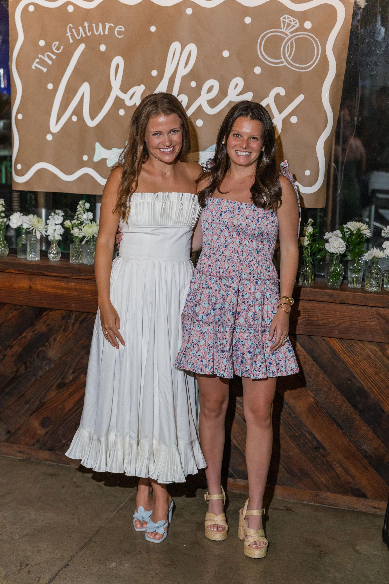 Two smiling women posing at a bridal shower in front of a future Walkers sign.