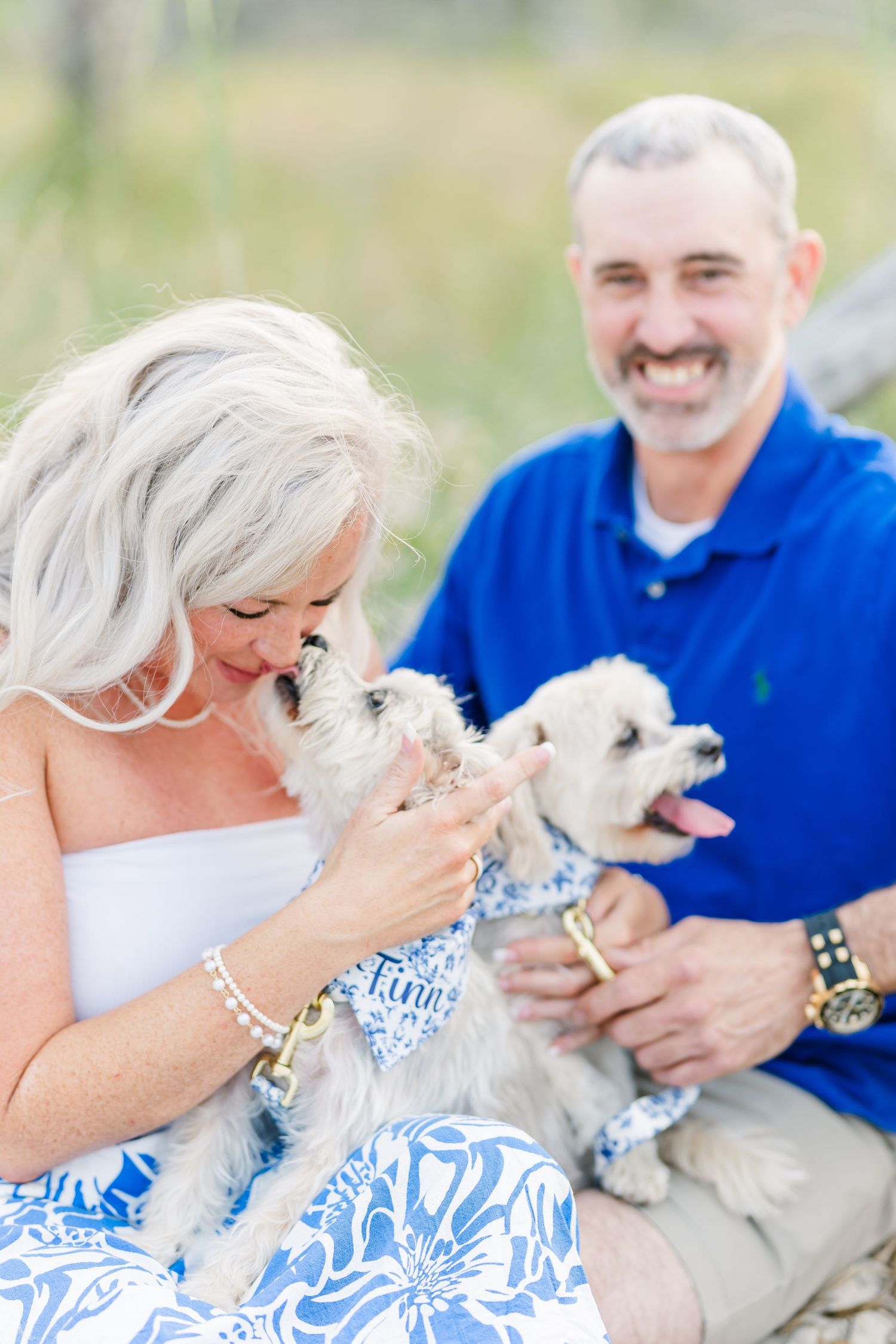 Joyful moment captured with couple and their small white dogs during beach photoshoot.