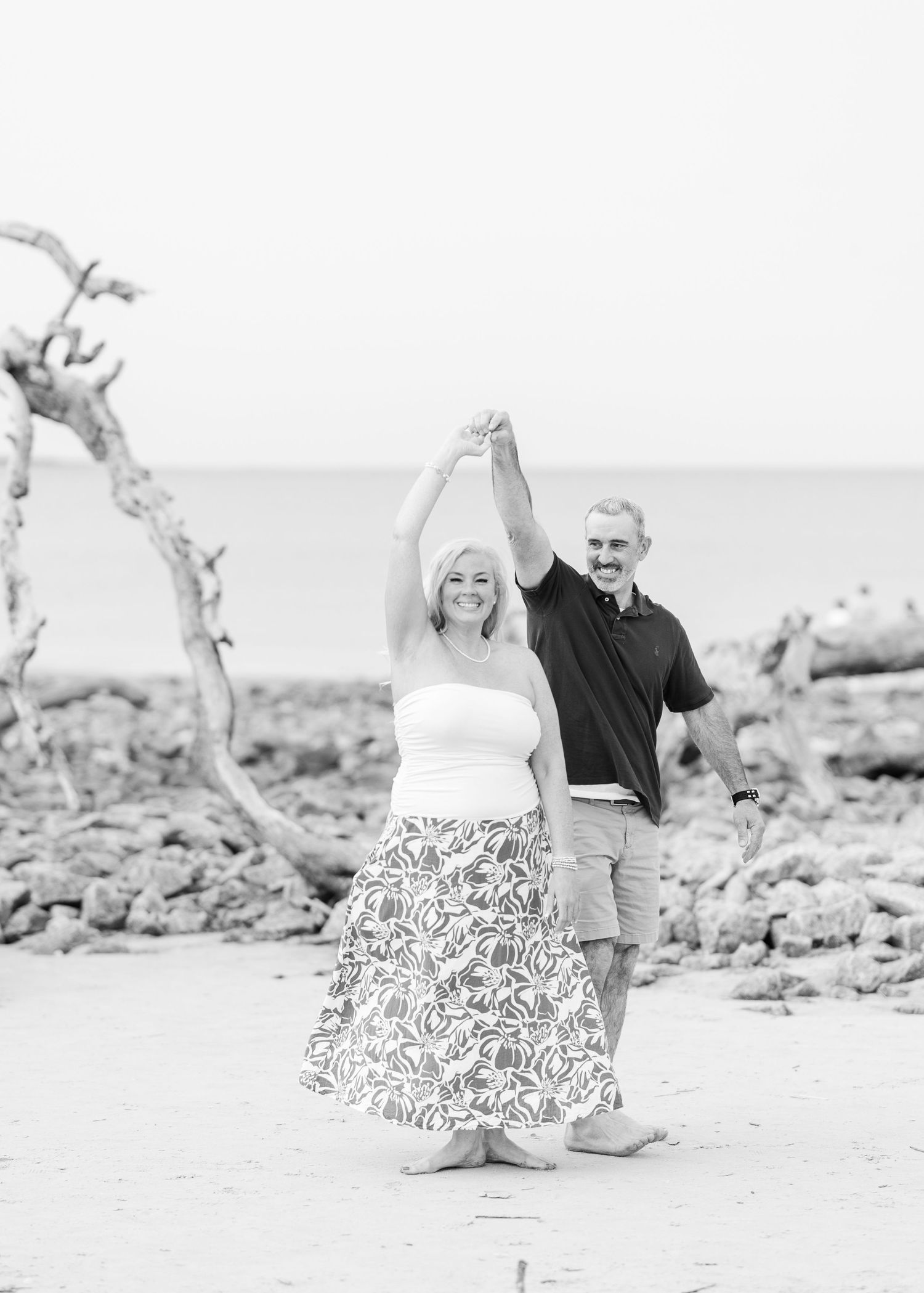 A series of black and white photos showing a couple dancing playfully on a rocky beach.