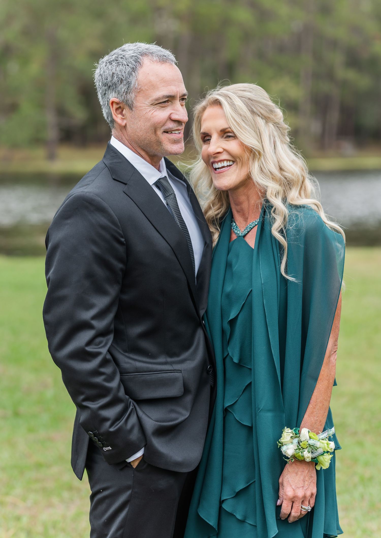 Elegant couple in formal attire share a joyful moment outdoors.