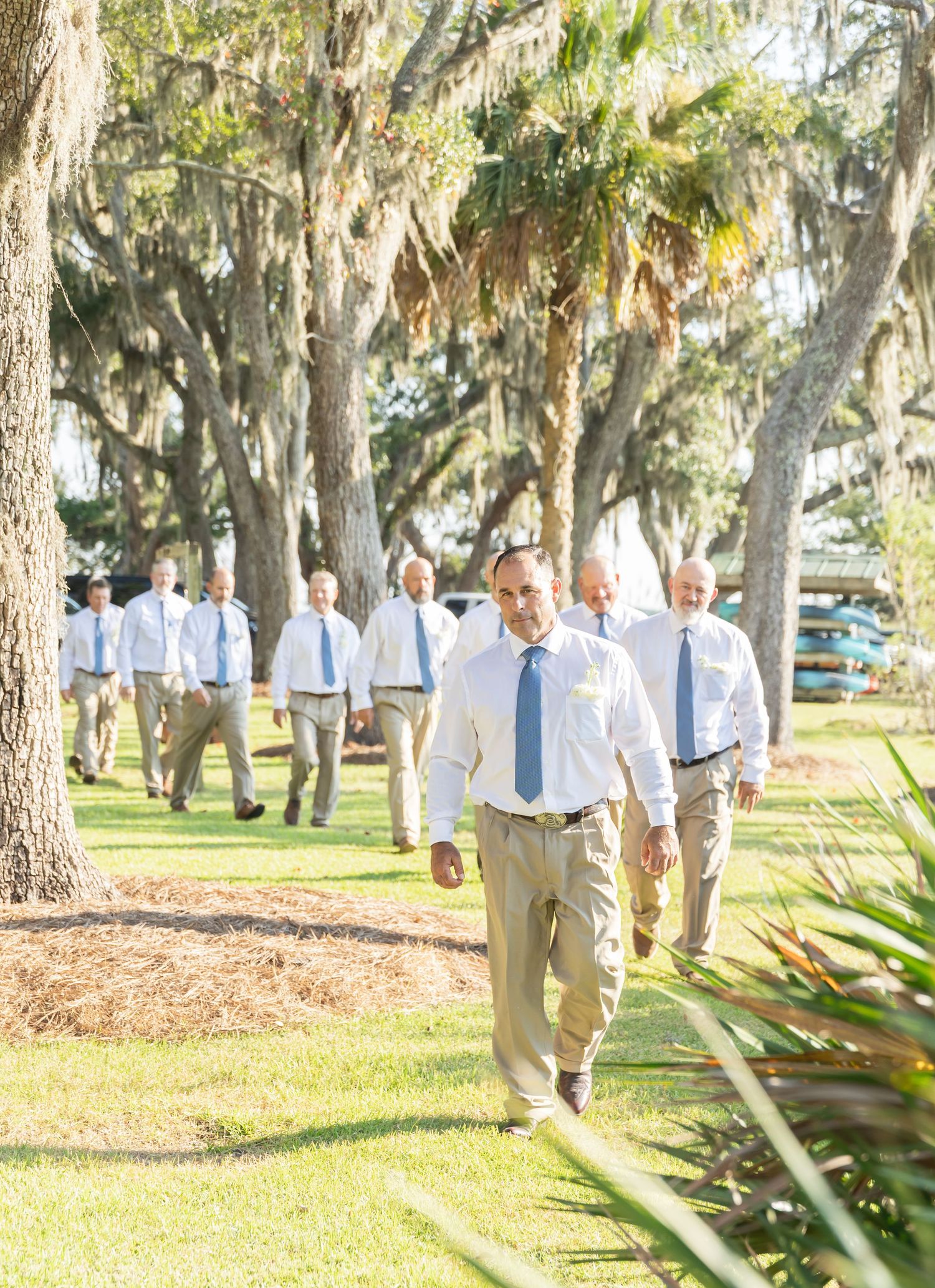 Group walking through a scenic garden path lined with Spanish moss covered oak trees.