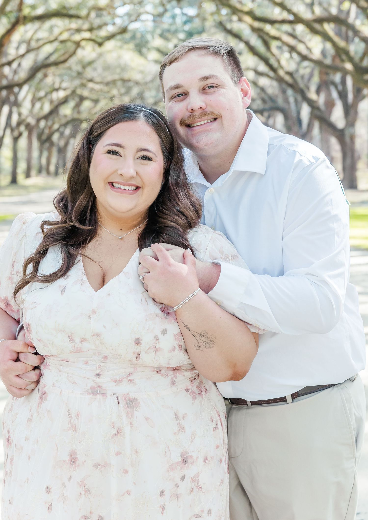 Couple shares intimate moment during engagement photoshoot in oak tree alley.