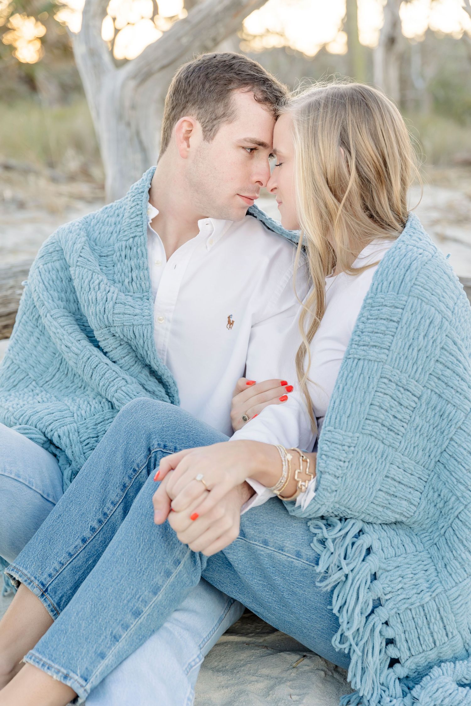 A couple in matching blue knit sweaters share an intimate moment while sitting together outdoors.