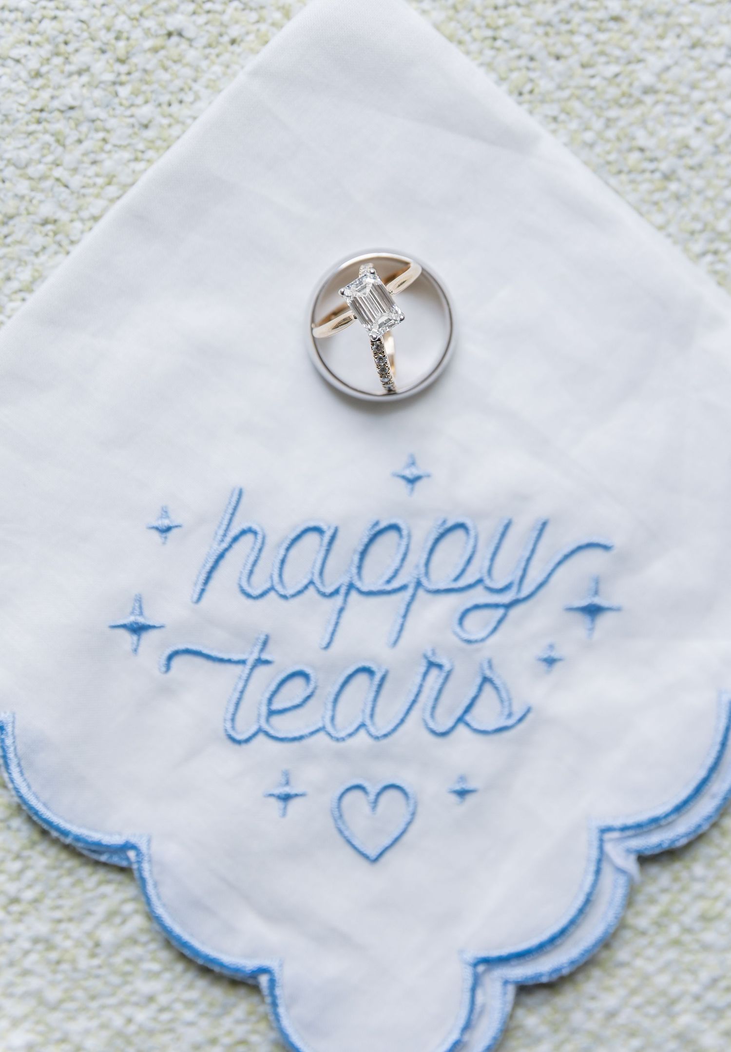 White handkerchief with blue embroidered 'happy tears' text and wedding ring detail.