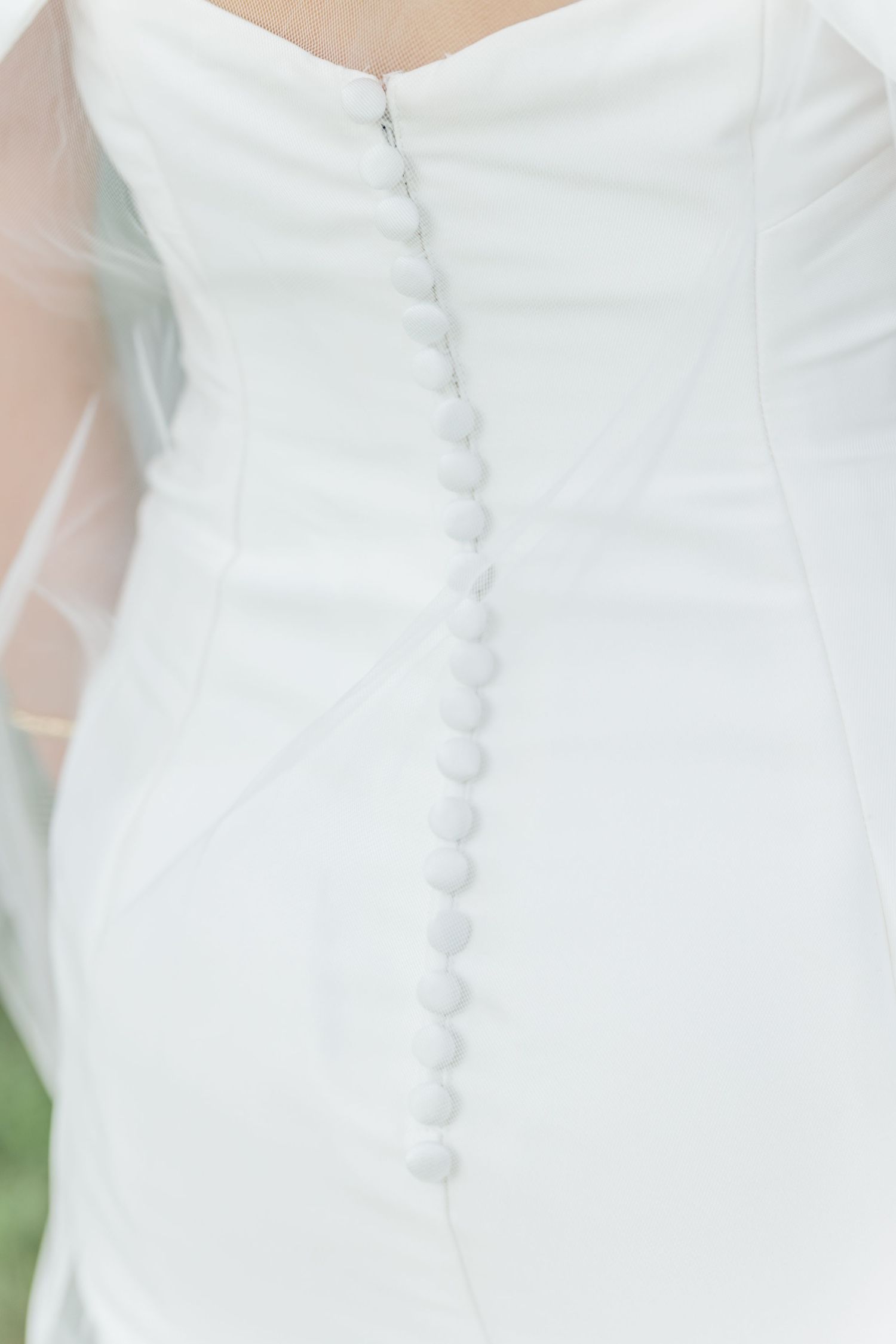 Detail shot of white button closures running down the back of a wedding dress.