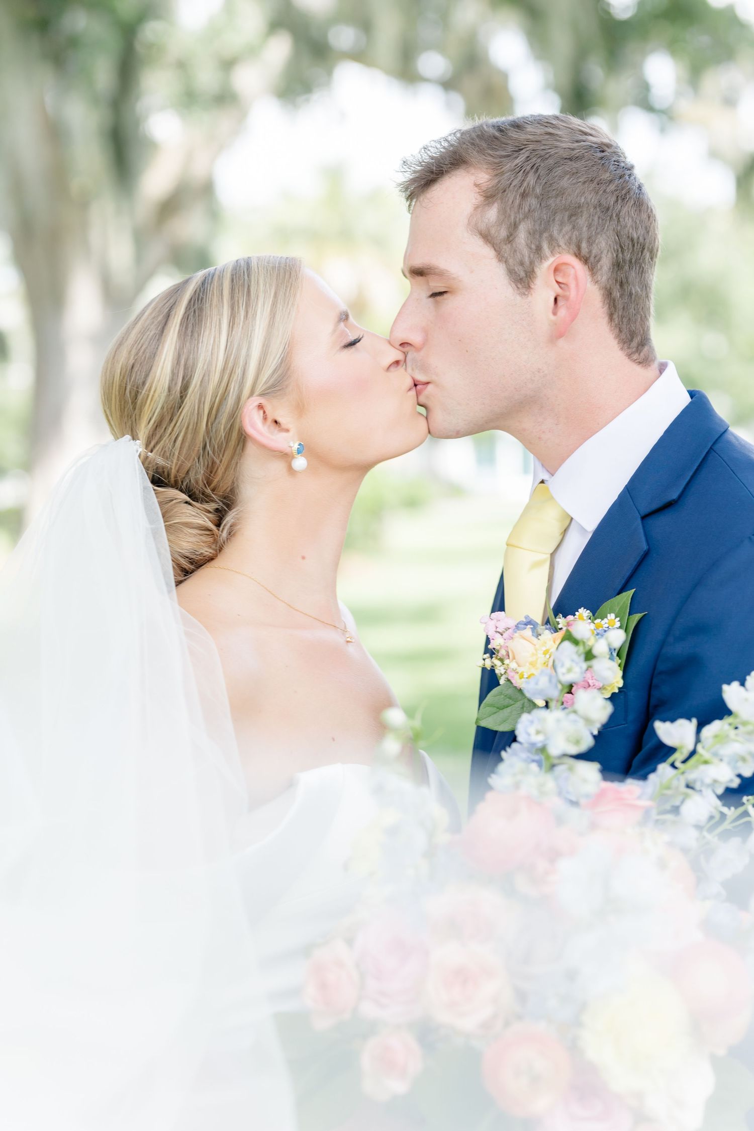 Romantic wedding kiss sequence captured against a soft, natural outdoor backdrop.