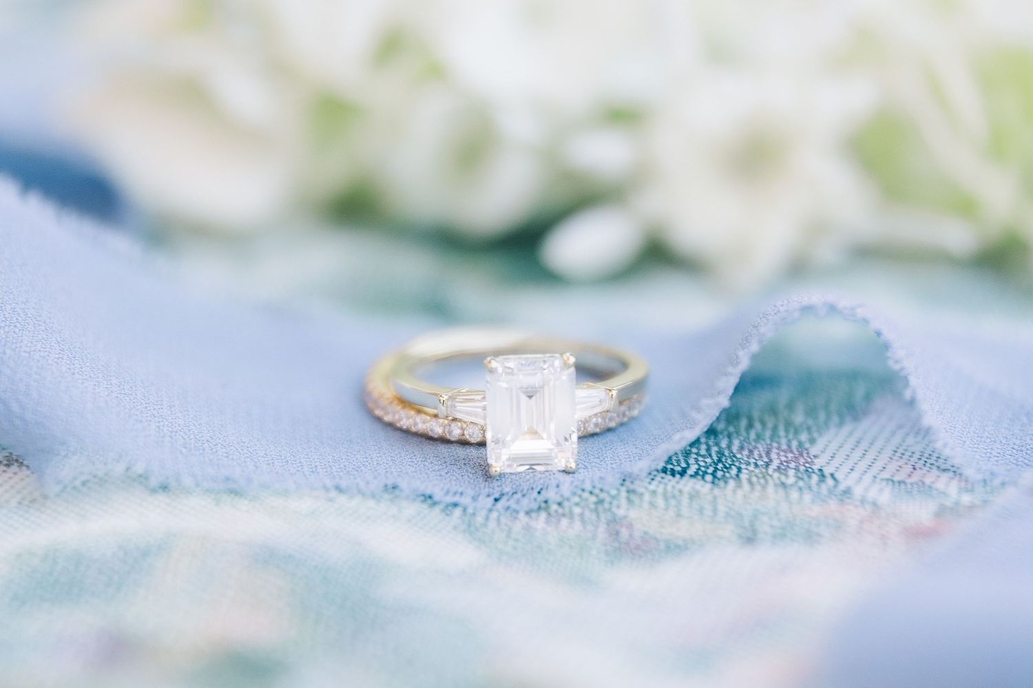 Close up detail shots of sparkling engagement rings with diamonds on a light blue backdrop.
