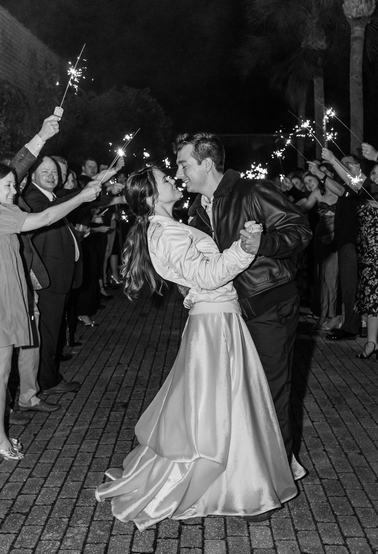A couple dancing at their wedding reception surrounded by guests holding sparklers creating a magical nighttime exit.