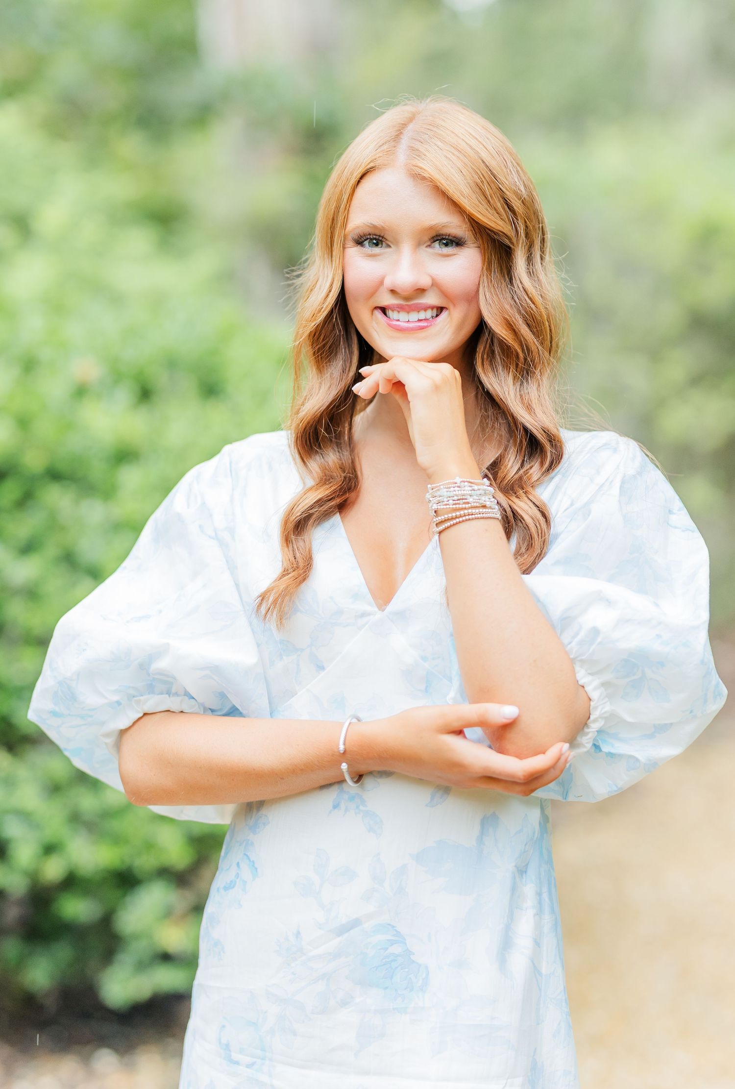 Portrait series outdoors featuring expressive poses in a white summer dress against a natural green background.