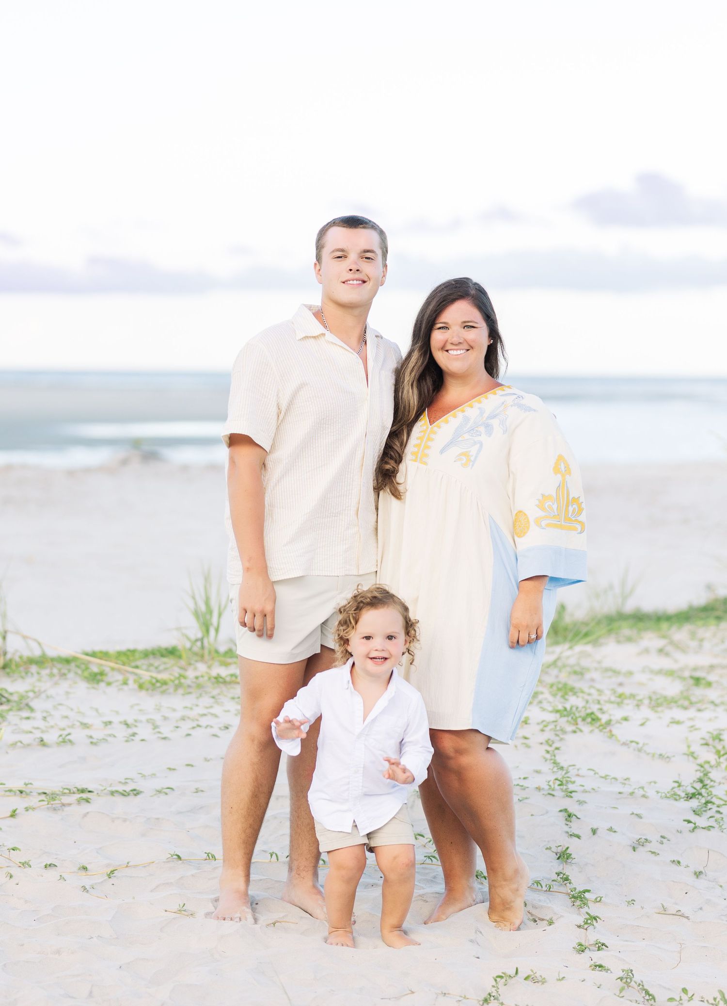Family portrait session on a beautiful beach at sunset with coordinated outfits.