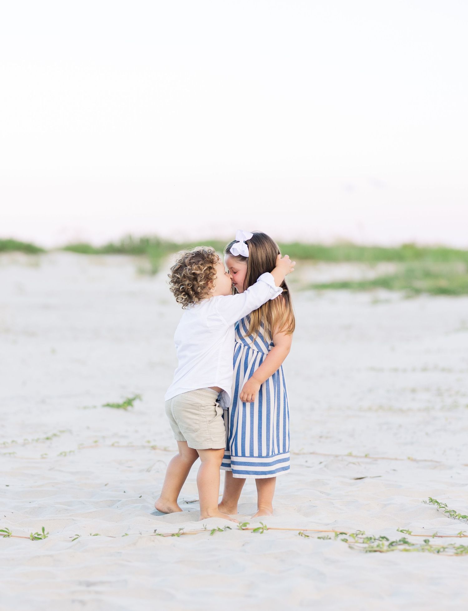 Two children share a sweet hug while playing on the beach.