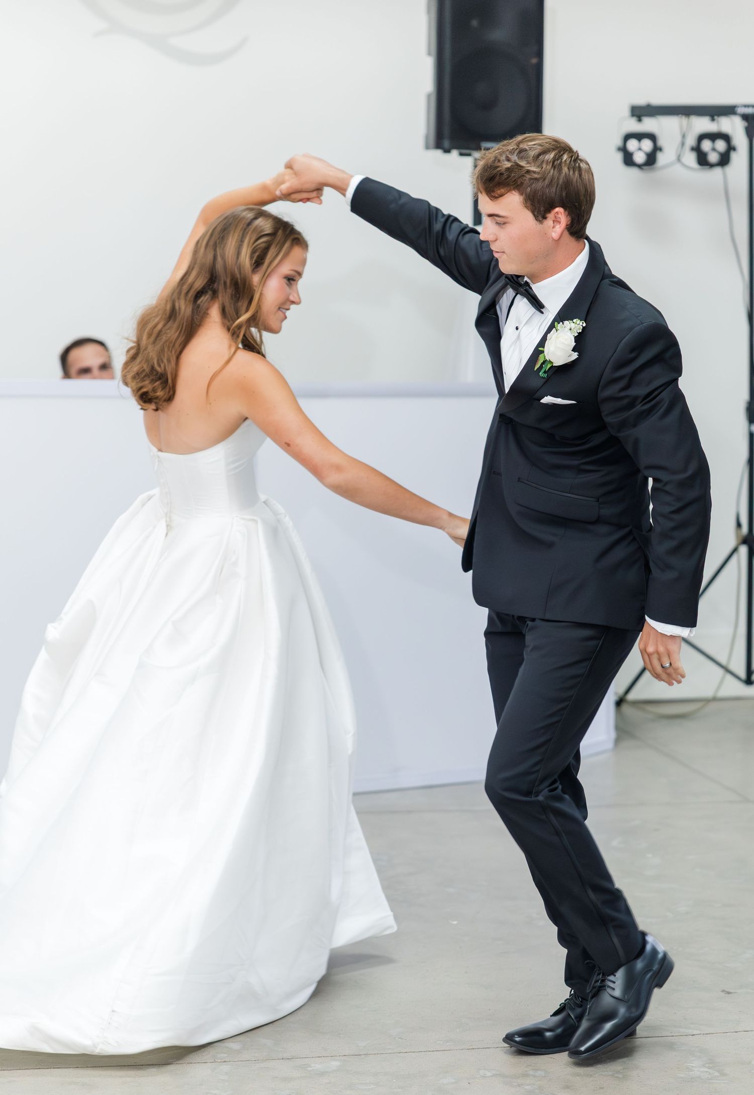 Bride and groom sharing a lively first dance, groom spinning bride in wedding attire.