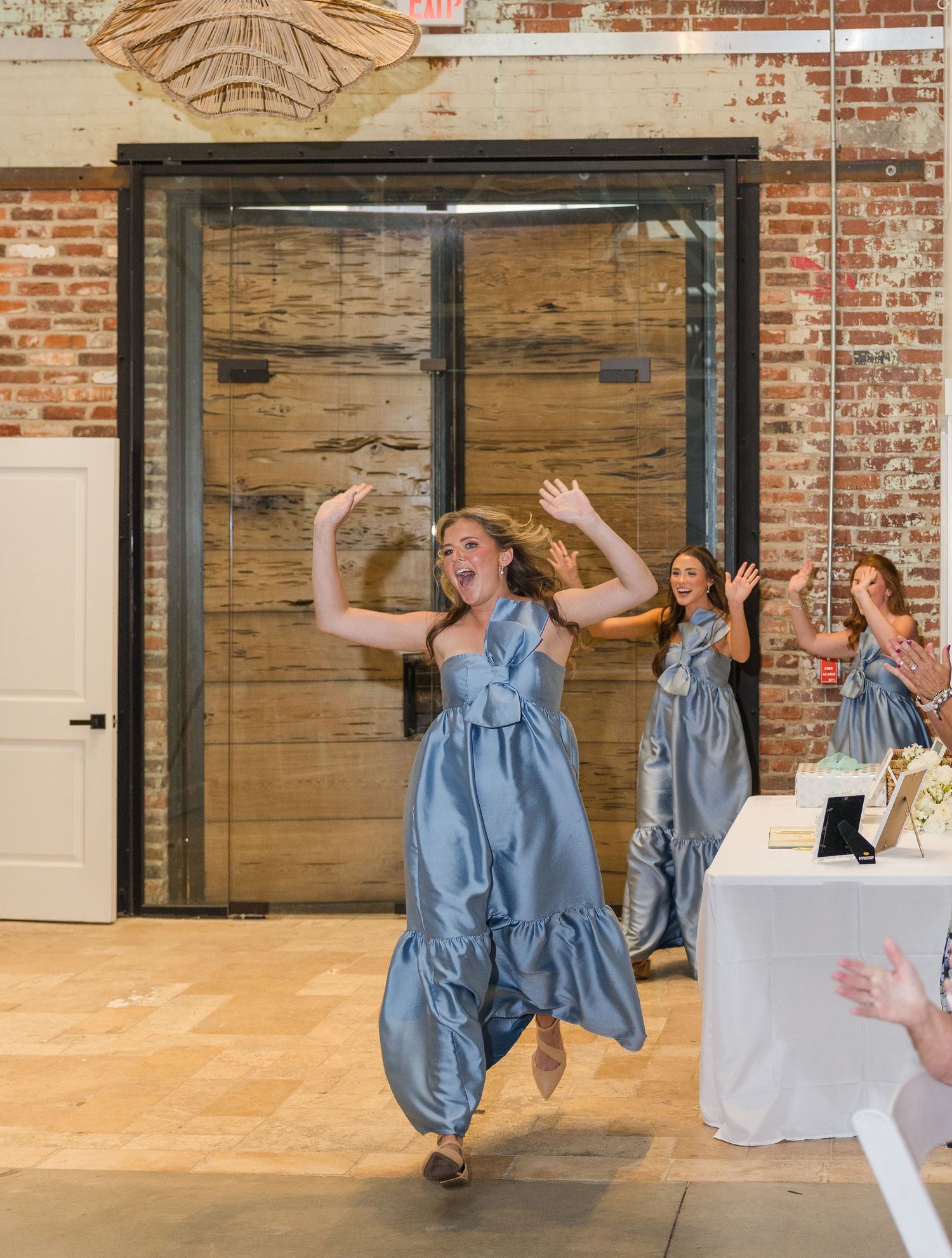 Excited bridesmaid in blue satin dress makes grand entrance at wedding reception.