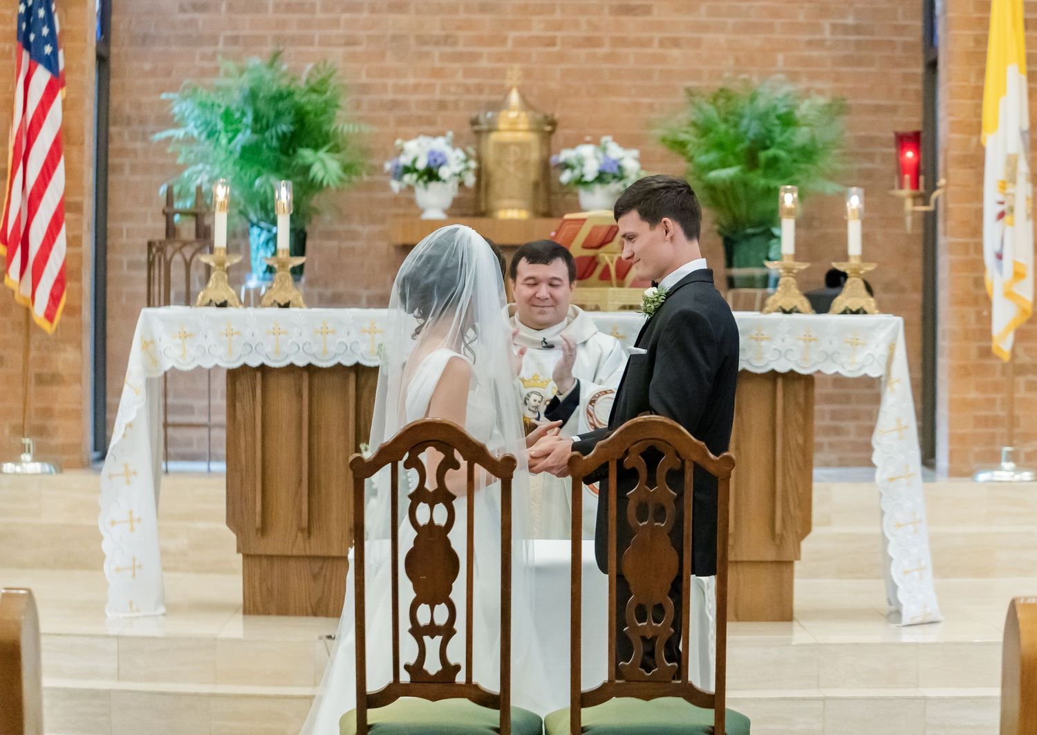 Church altar decorated with American flags, wooden chairs, and floral arrangements.