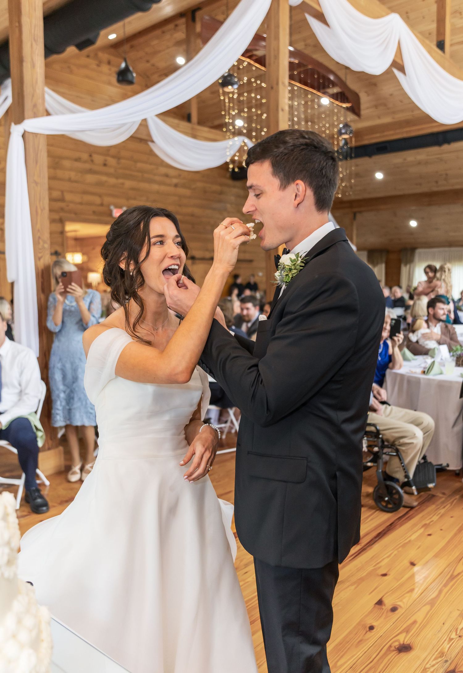 Wedding couple shares their first dance in a wooden barn venue decorated with white draping.
