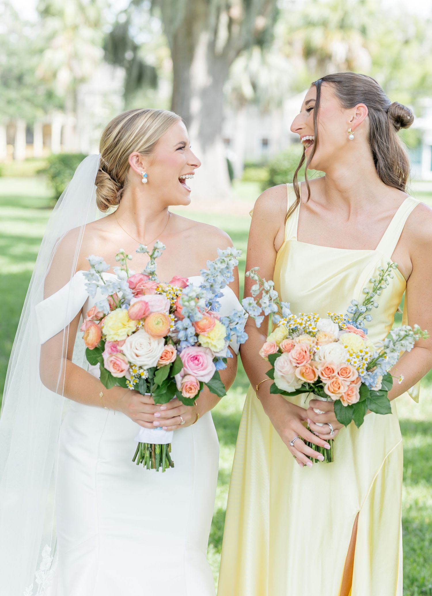Close-up of colorful spring bouquets held by bridesmaids in yellow and white dresses.