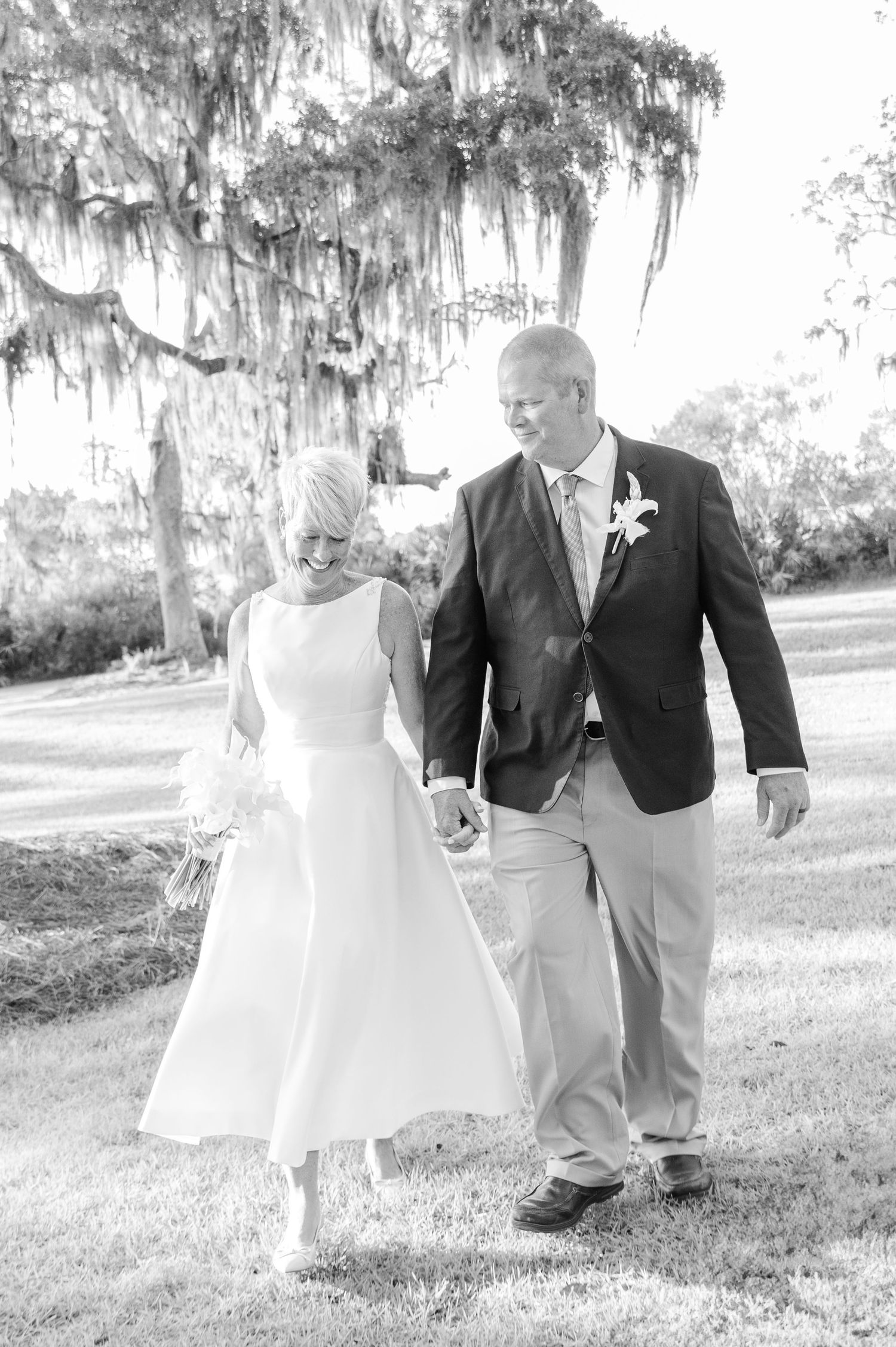 Black and white photo series of a couple dancing playfully in a garden with Spanish moss hanging from trees.