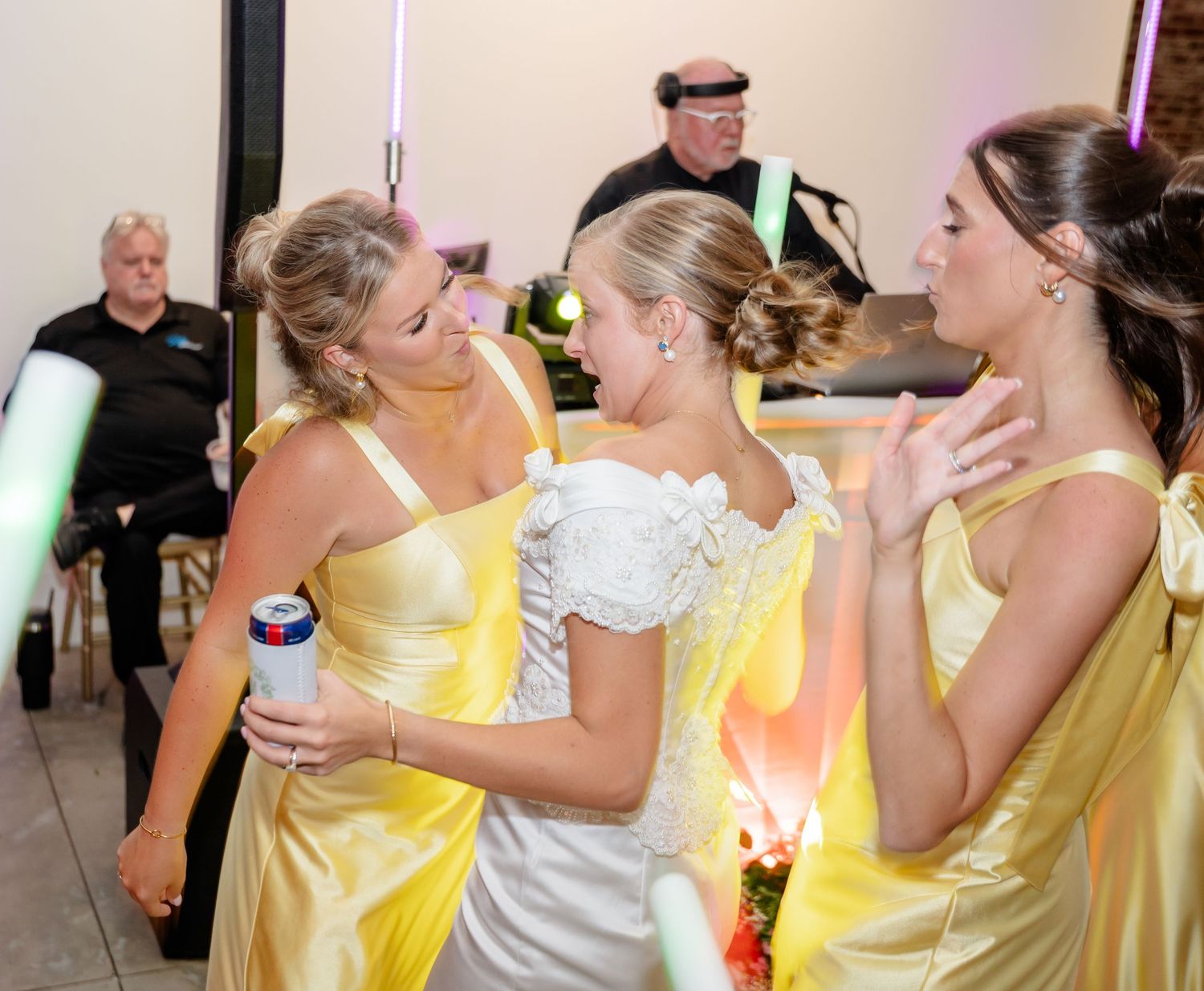 Guests in yellow and white attire celebrate with glowing party accessories.