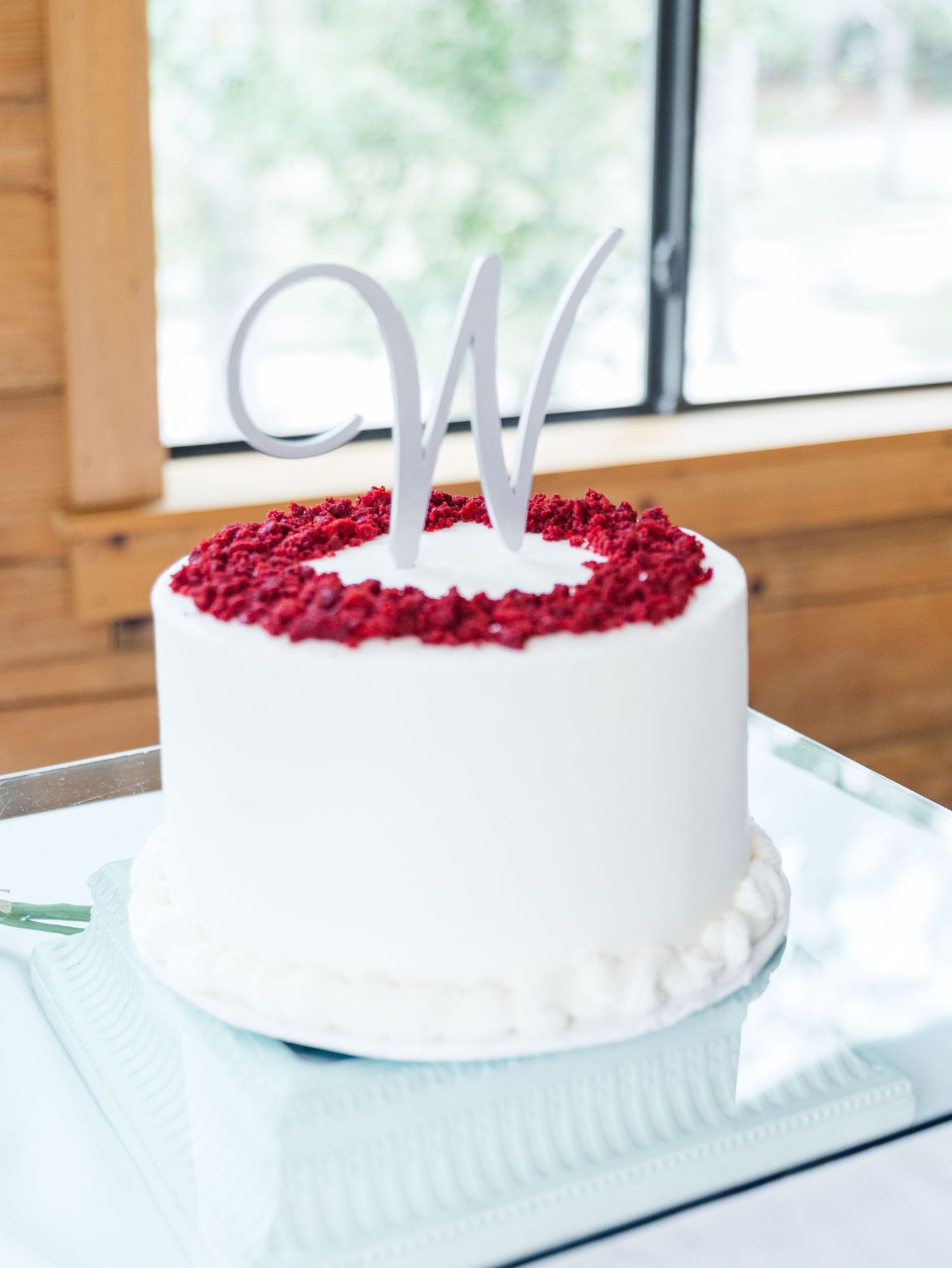 White frosted cake decorated with fresh red raspberries in a circular pattern on top.