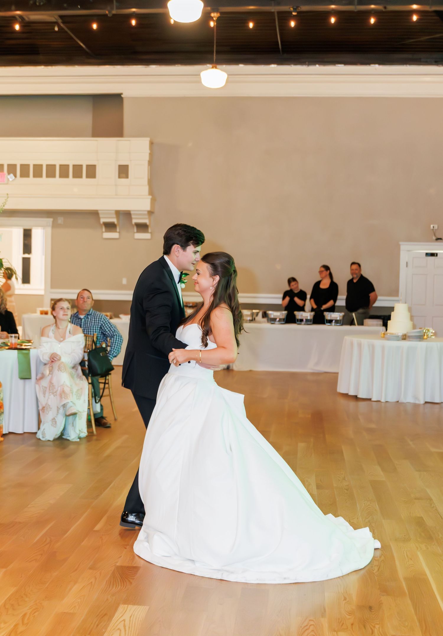 Bride and groom share their first dance on a wooden floor at an elegant wedding reception venue.