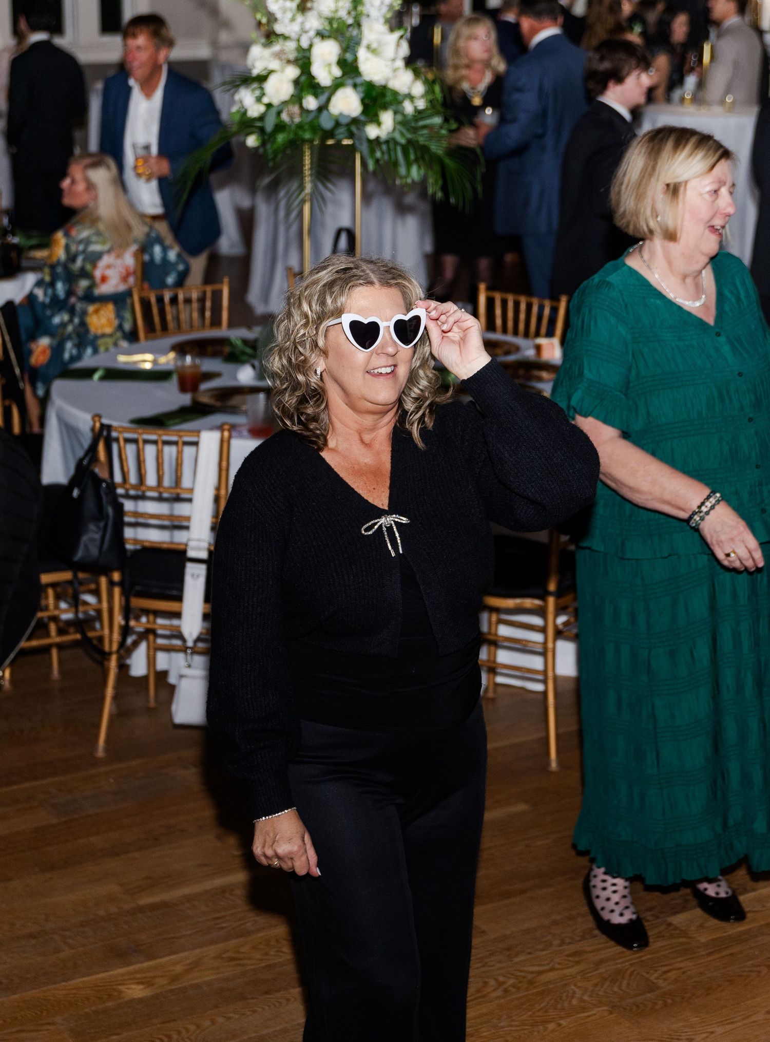Woman wearing heart-shaped sunglasses dances at a wedding reception party.