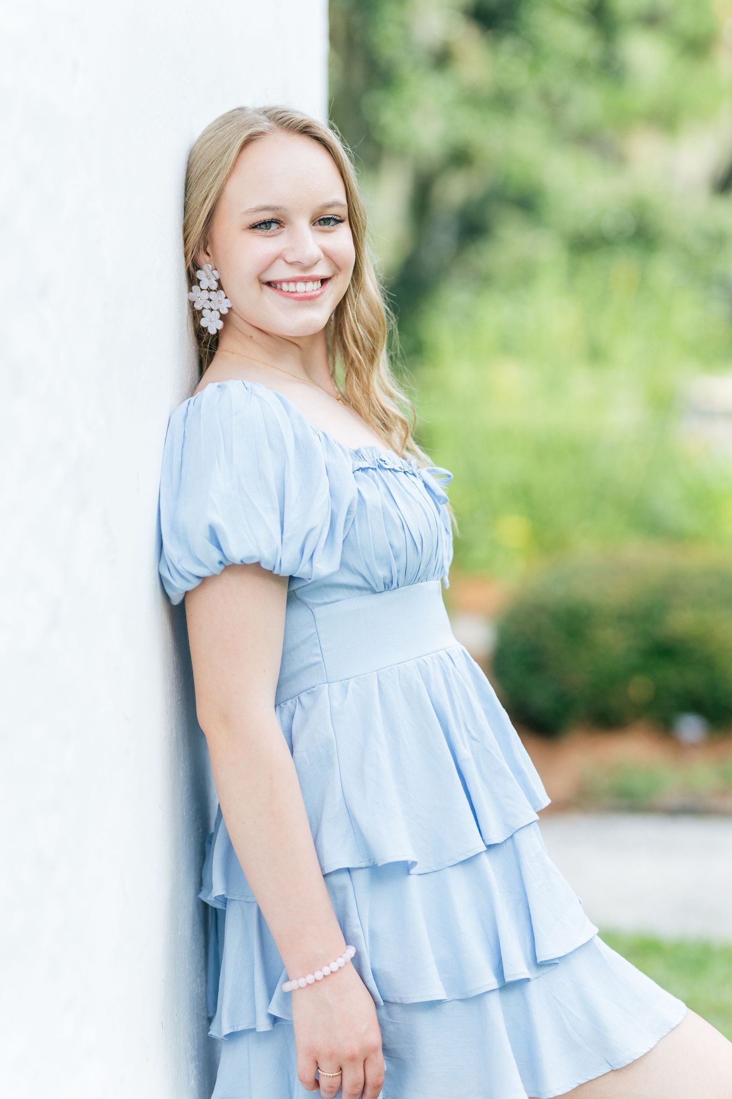 Light blue ruffled dress with short puff sleeves photographed against green outdoor background.