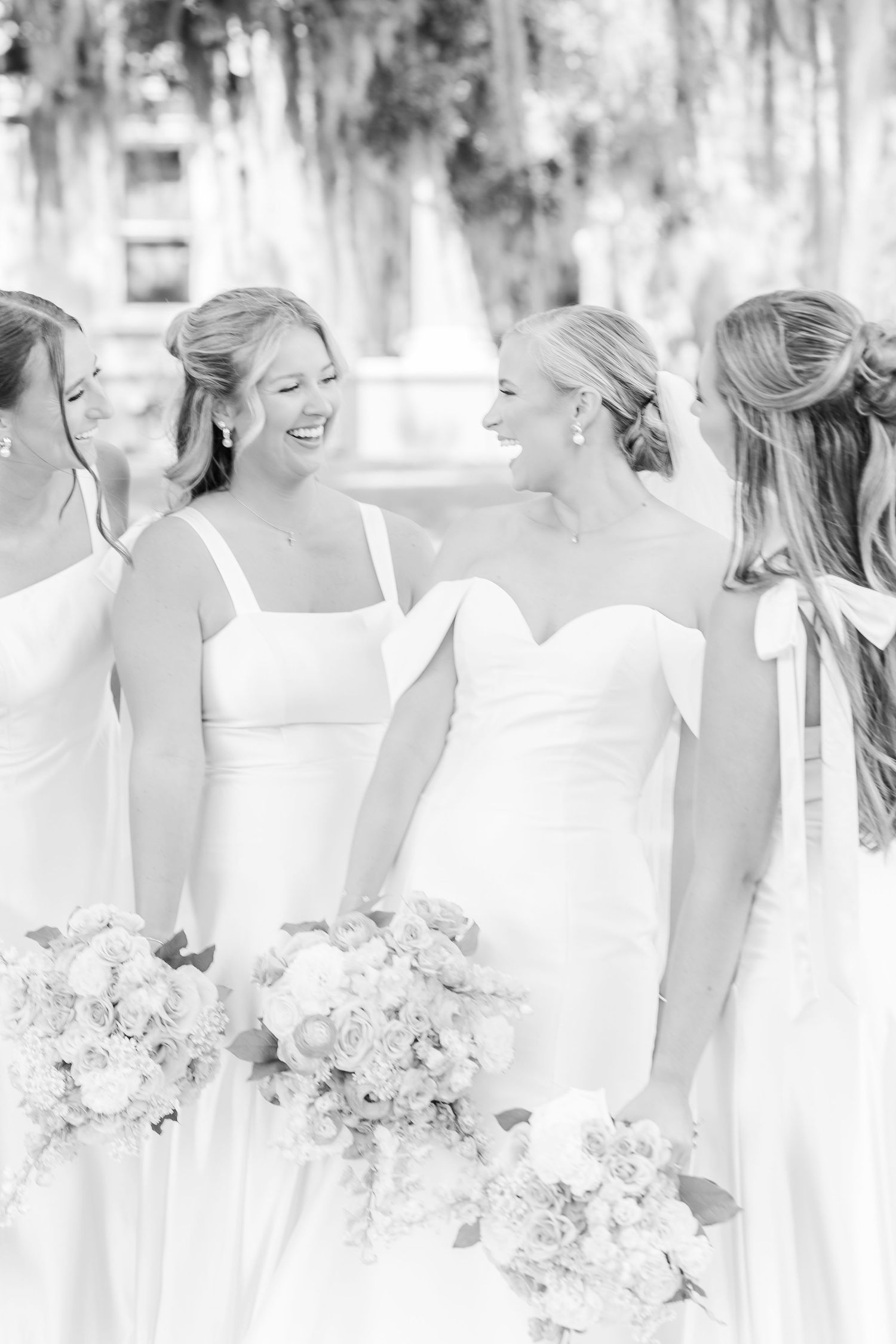 Black and white photo of bridesmaids in white dresses holding floral bouquets.