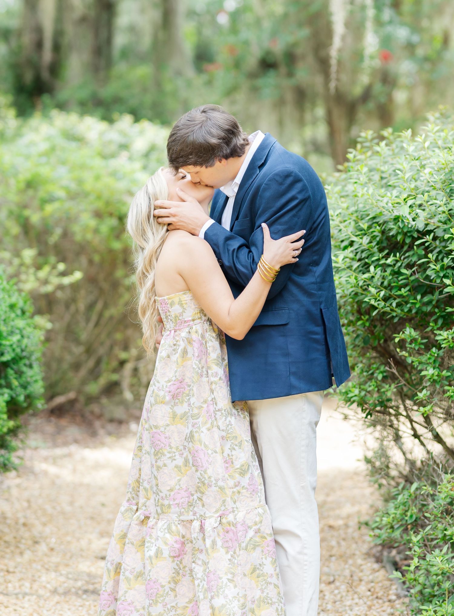 Couple sharing intimate moments on a garden path surrounded by lush greenery.