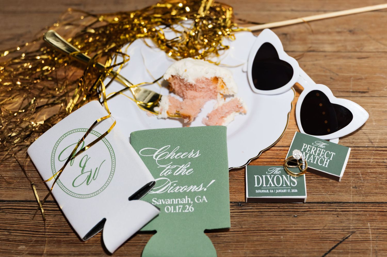 Wedding favors and decorative items including heart-shaped sunglasses and drink koozies arranged on wooden surface.