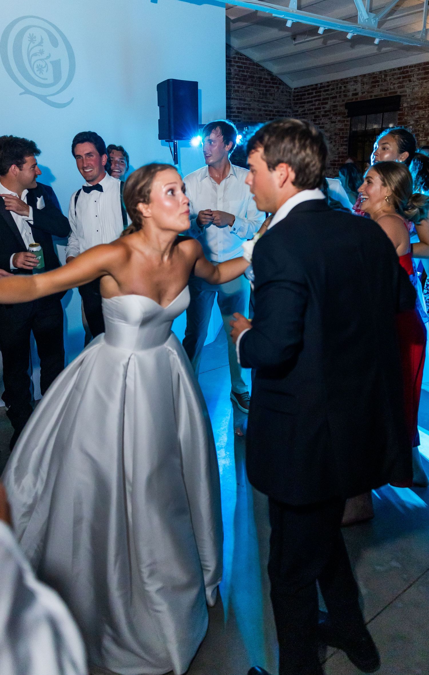 Bride in silver ball gown dancing with groom at elegant wedding reception with guests watching.