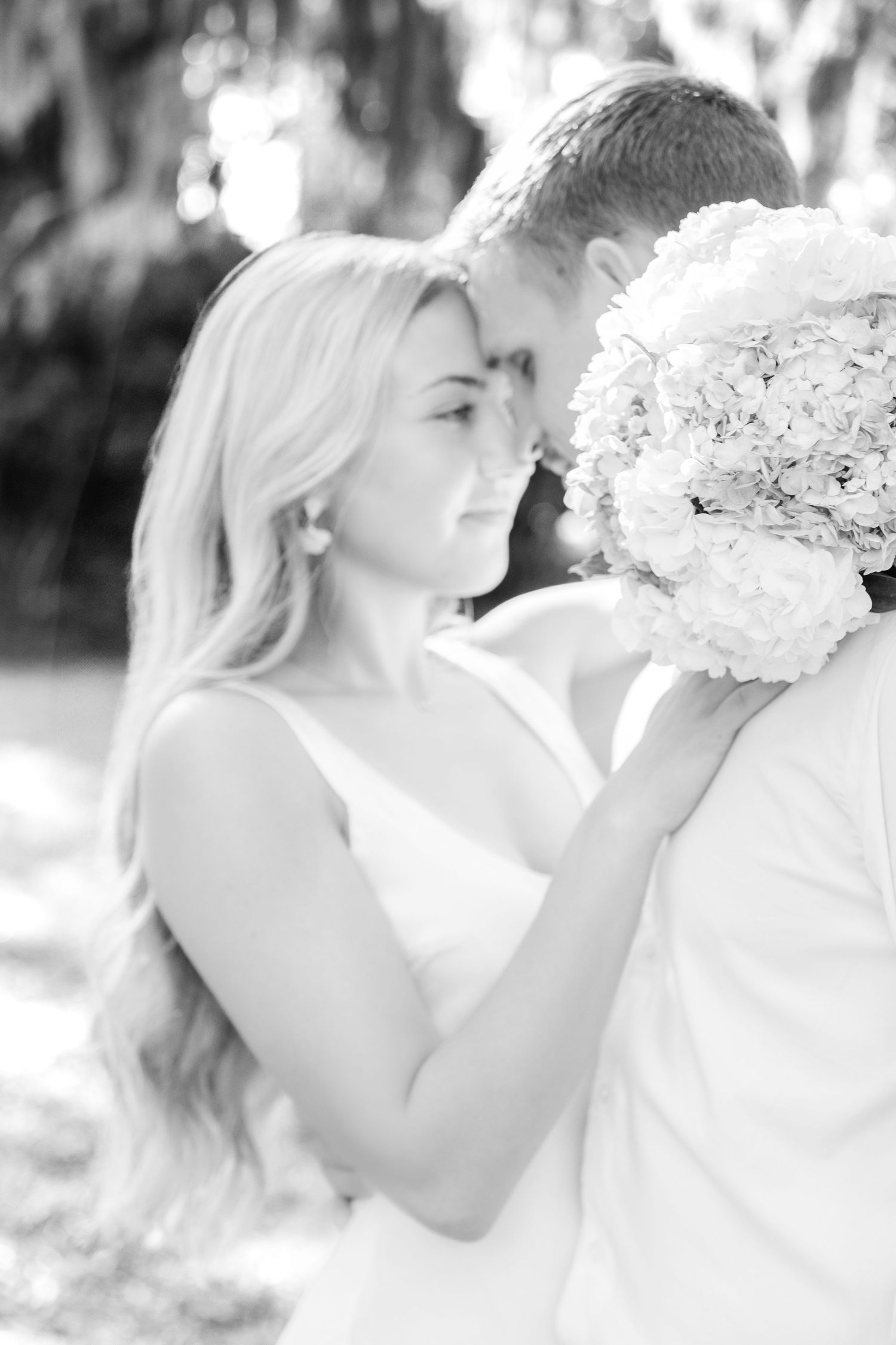 A romantic black and white portrait with a woman holding a white floral bouquet.