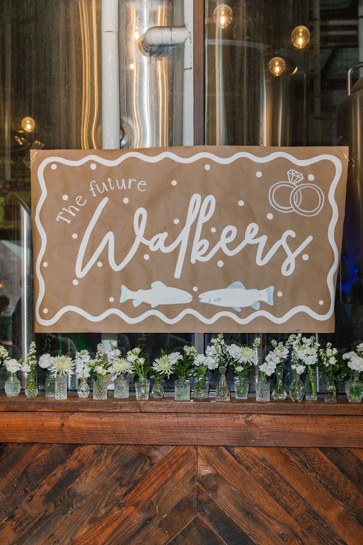 Handmade 'The Future Walkers' engagement party banner with rings and fish on kraft paper.