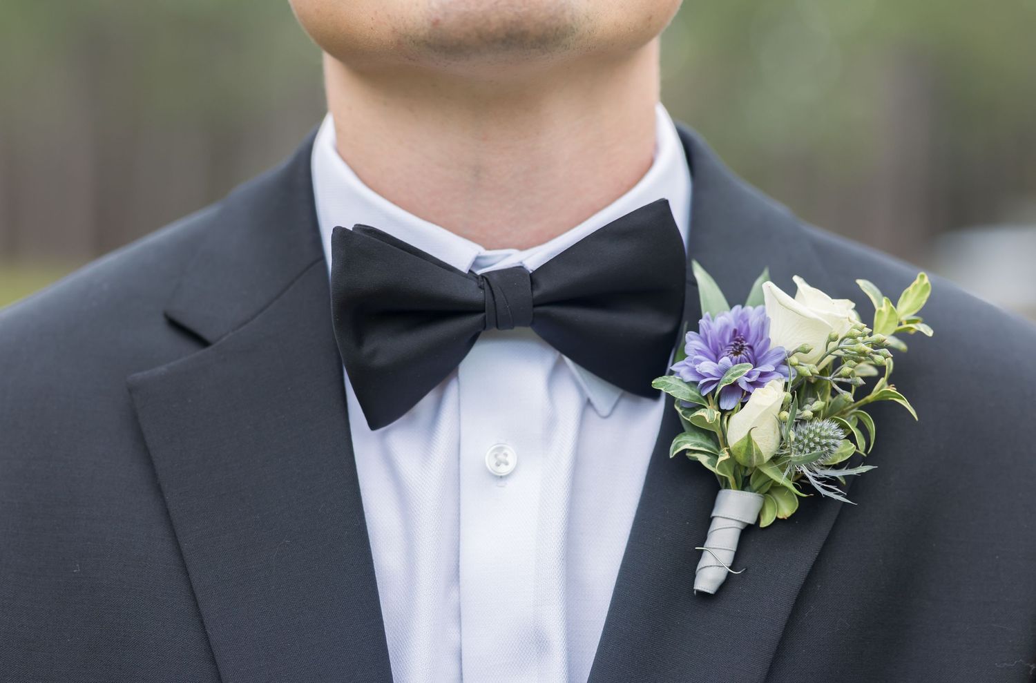 Close-up view of formal black bow ties and boutonniere flower details on wedding attire.