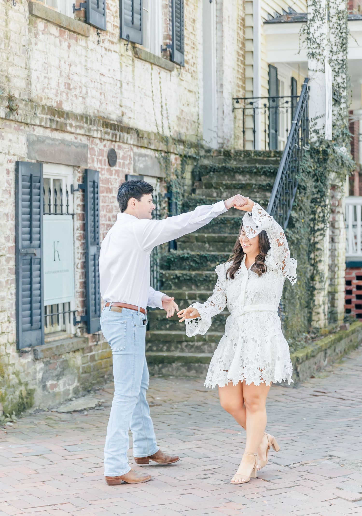 A couple dances on a brick pathway while wearing coordinated white and blue outfits.