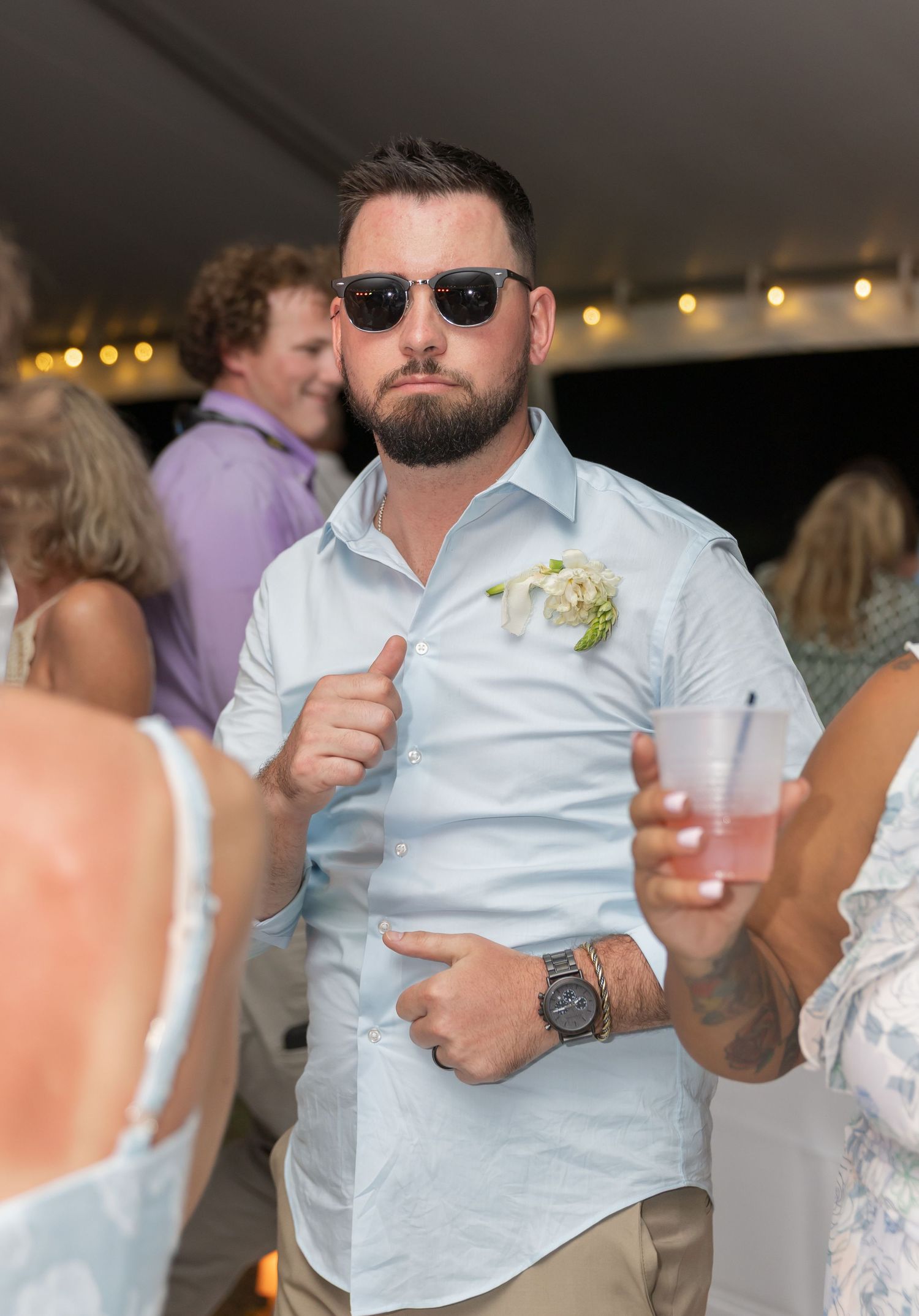 Wedding guests dance and celebrate on the dance floor with drinks in hand.