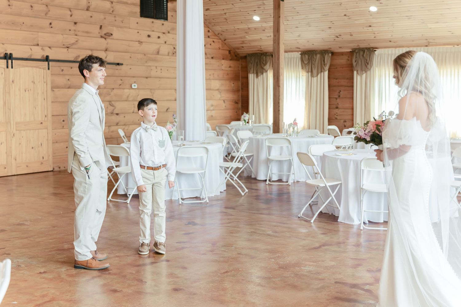 Wedding ceremony preparations in a rustic barn venue with white folding chairs.