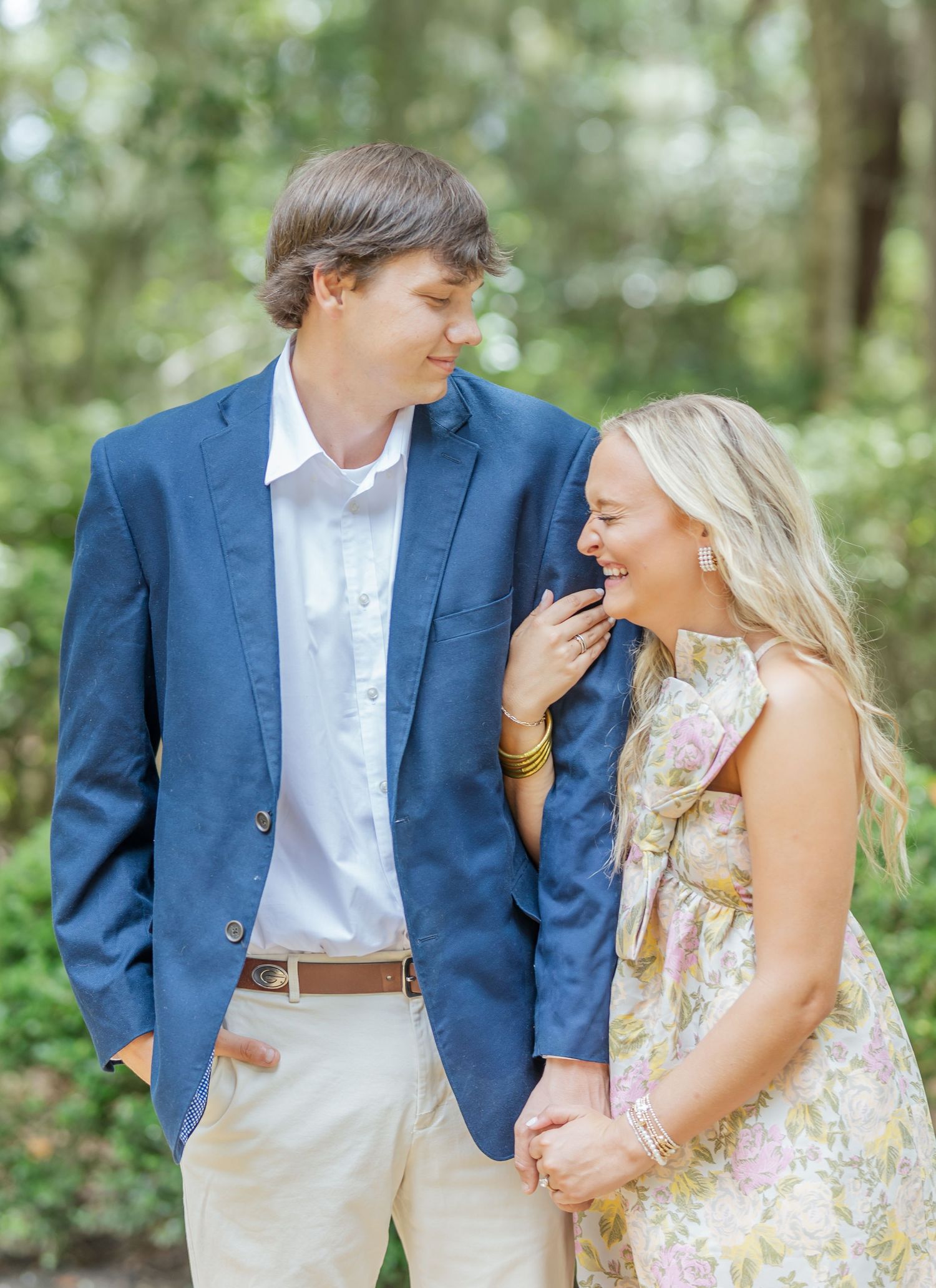 Couple in coordinated blue and white outfits share romantic moments in an outdoor photoshoot among trees.