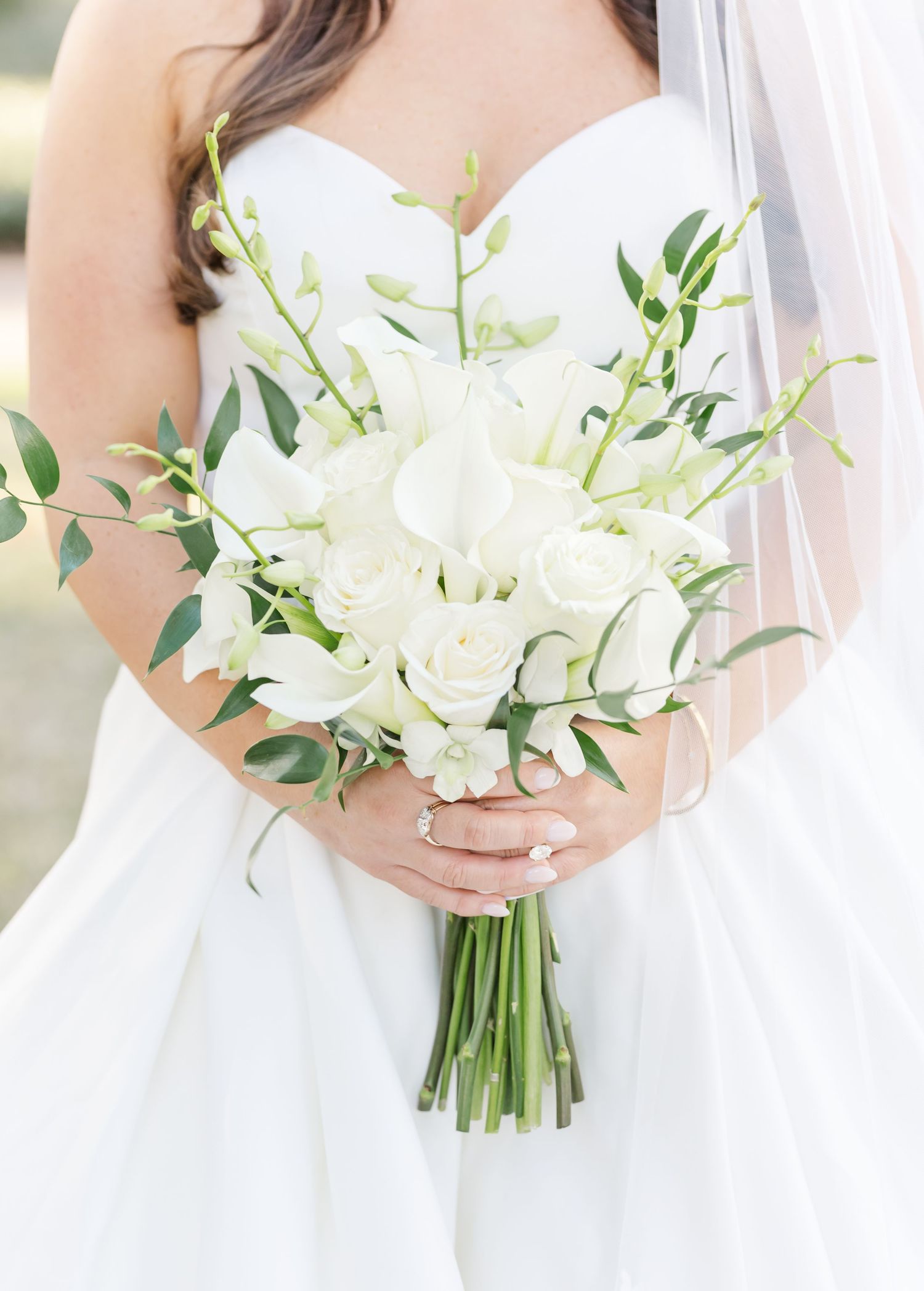 Elegant white bridal bouquet with cascading orchids and delicate greenery against a soft background.