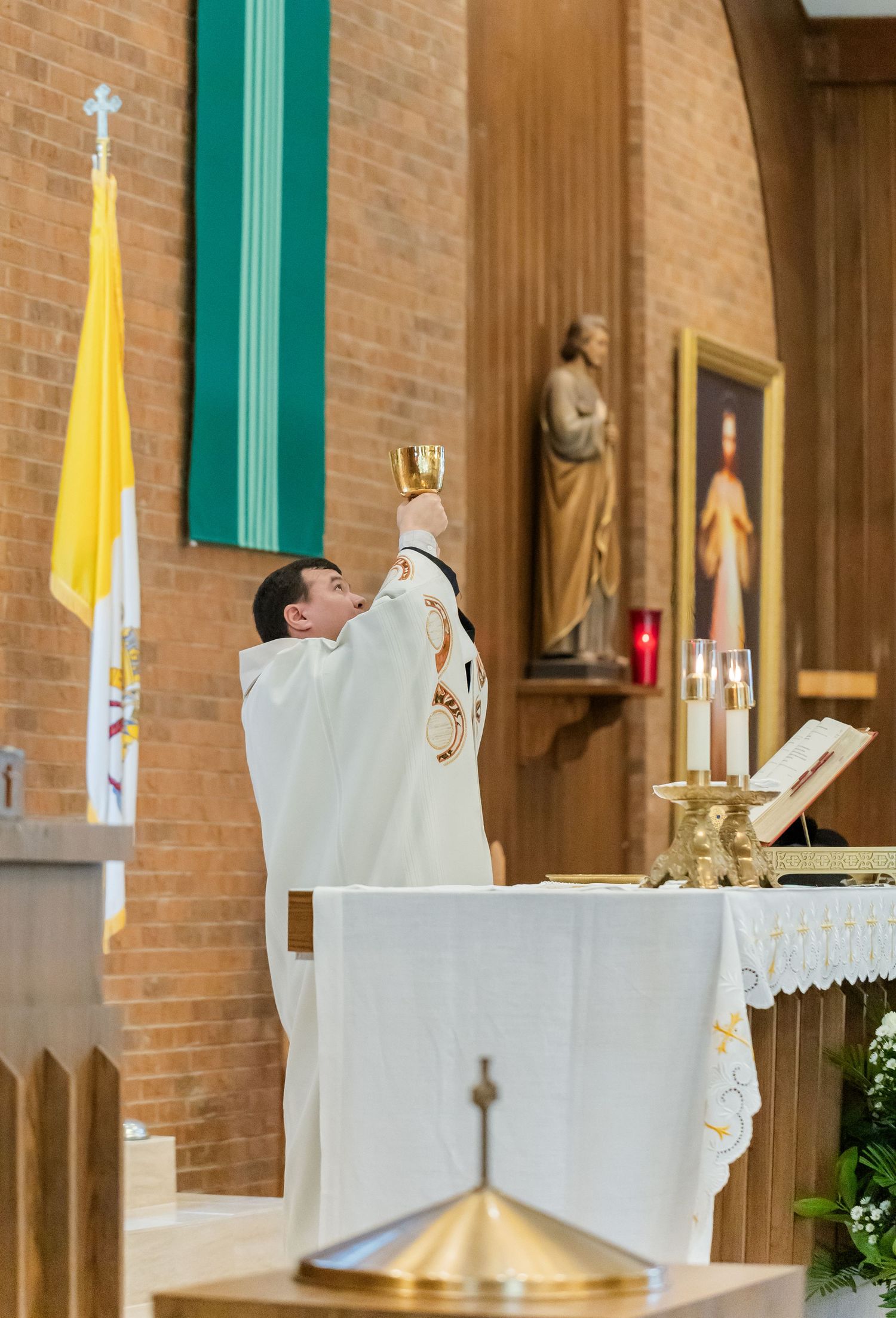 White altar cloth and decorations in Catholic church sanctuary during wedding ceremony.