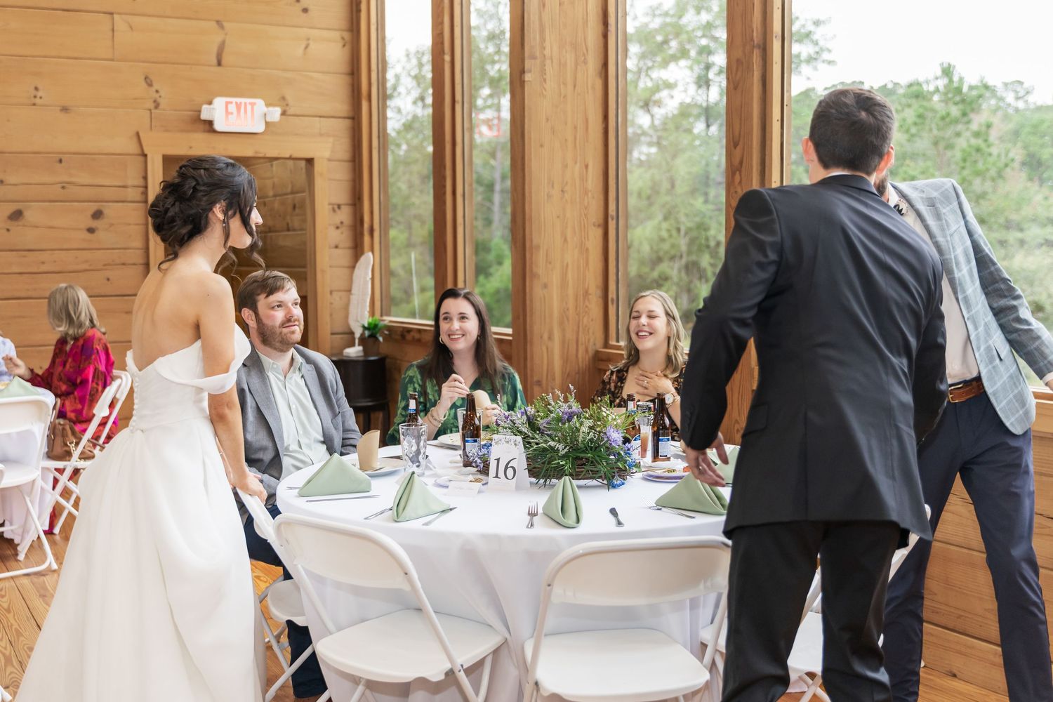Wedding reception scene in a wood-paneled venue with guests seated at decorated tables.