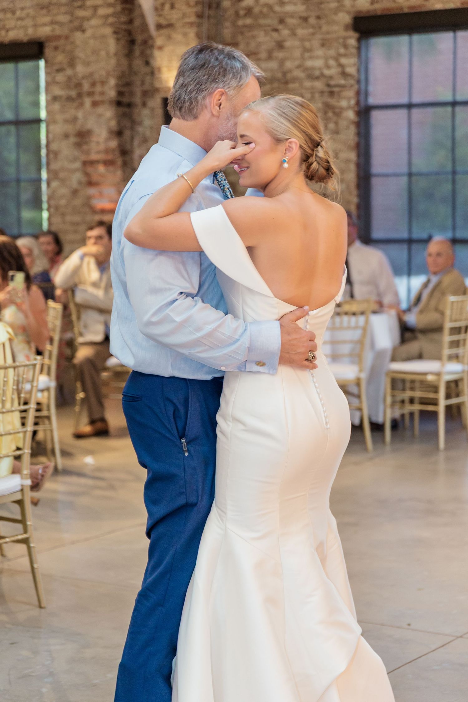 Couple sharing an intimate dance together at a rustic brick venue during their wedding reception.
