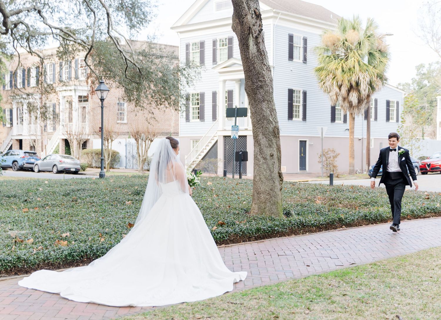 Wedding couple and attendants walk along brick pathways near historic Charleston buildings and palm trees.