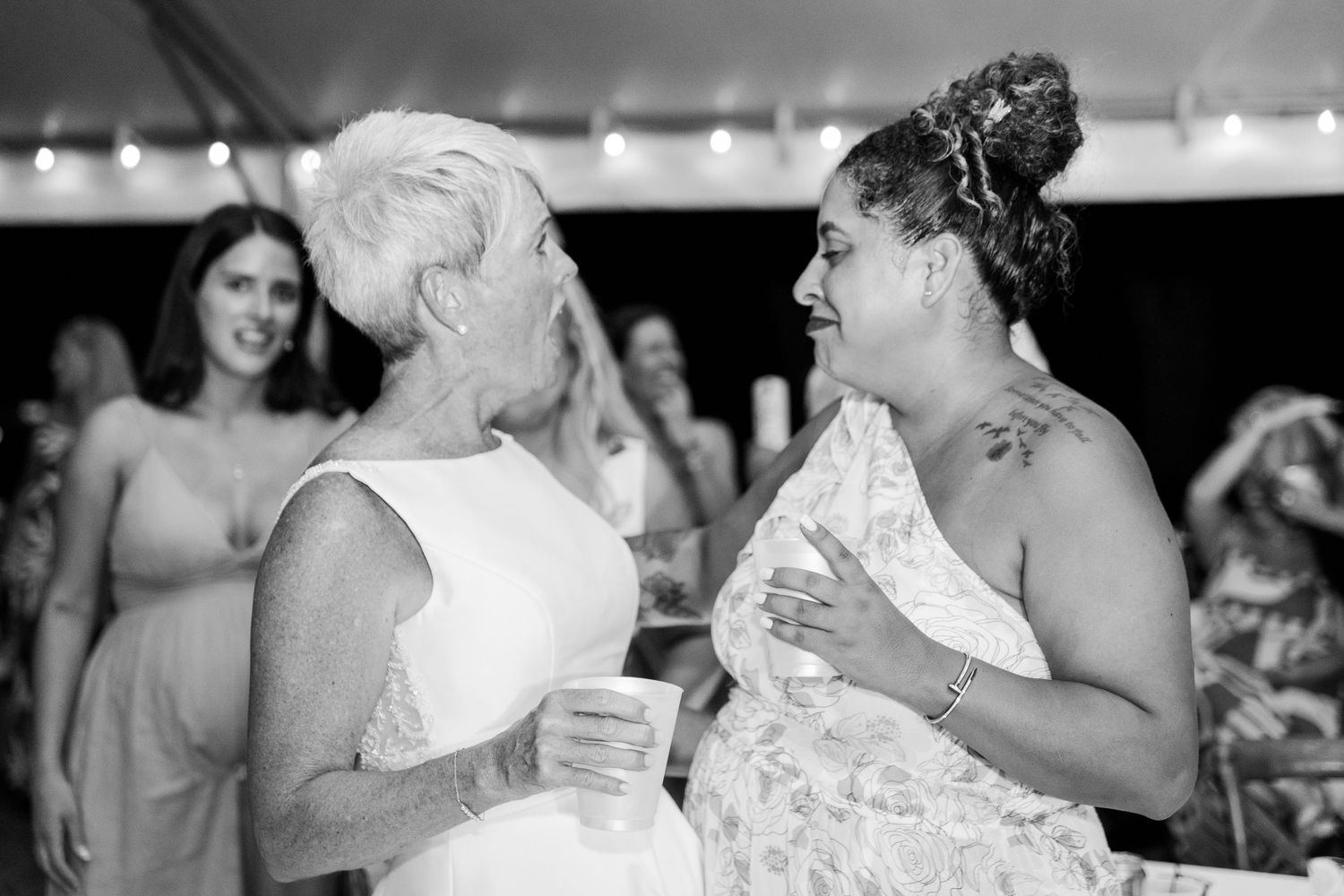 Black and white photo showing wedding guests dancing and celebrating at a lively reception party.