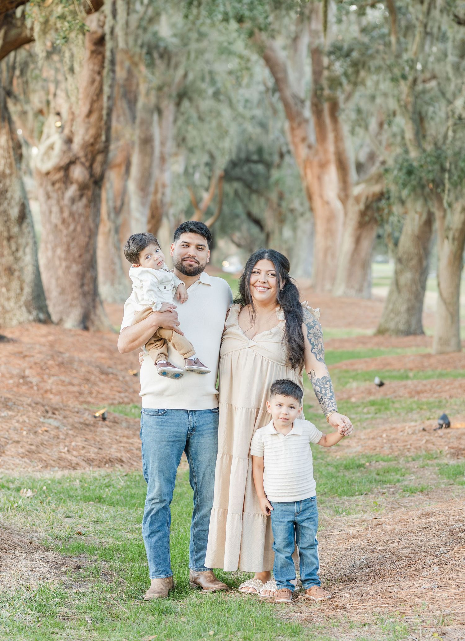 Family enjoying a playful moment together in a wooded park setting with eucalyptus trees in the background.