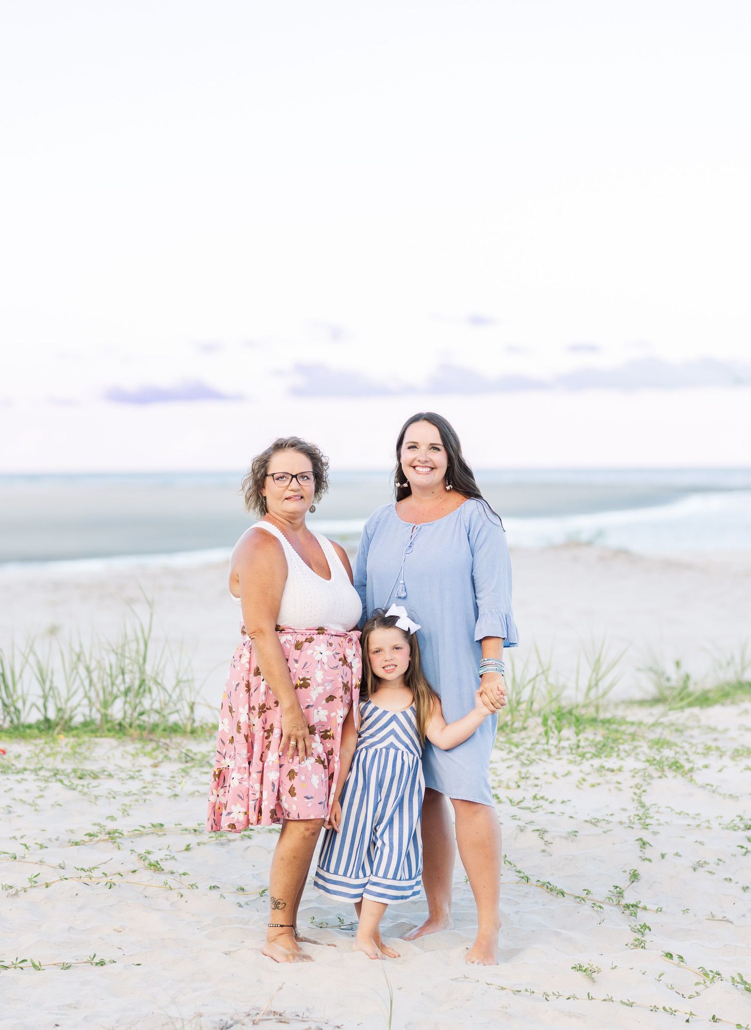 Group posing casually together on a bright sandy beach near the ocean.