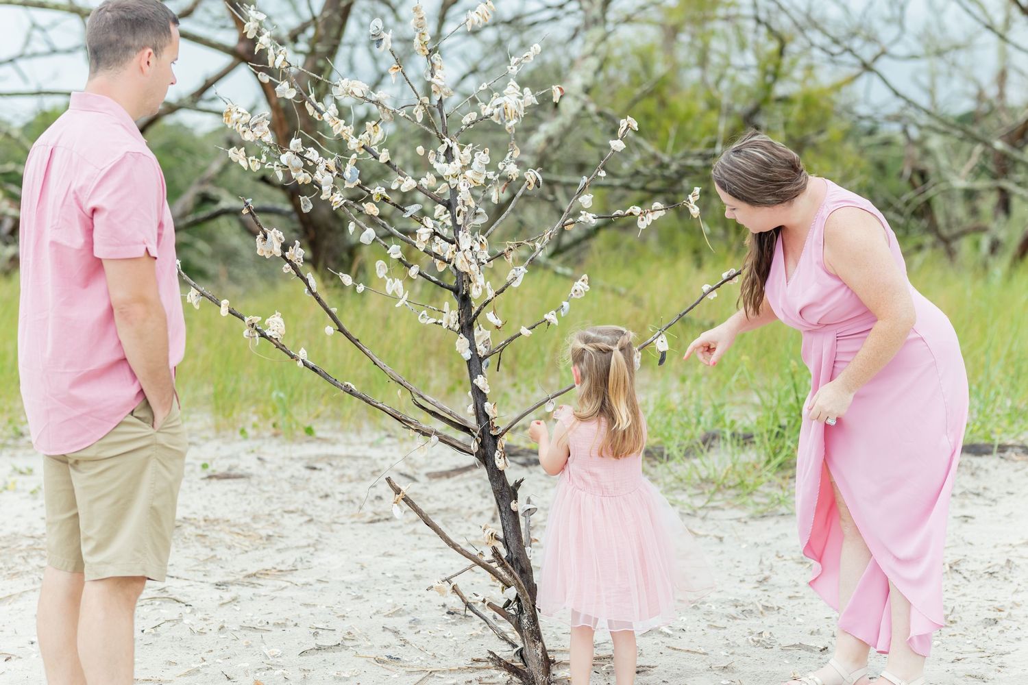 A series of pink-dressed individuals exploring and interacting with tree branches in a natural outdoor setting.